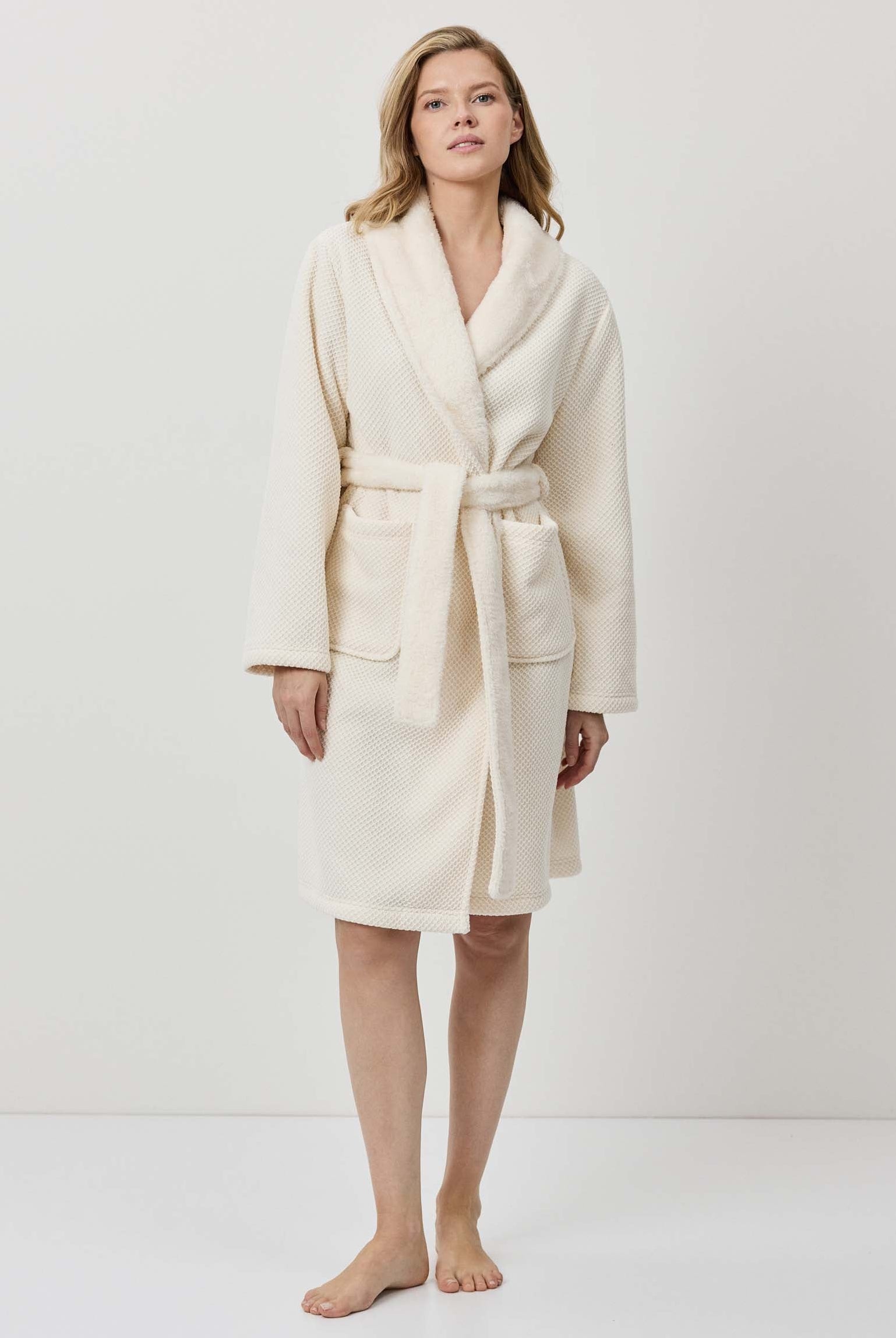 Woman wearing a cream-colored robe against a white background