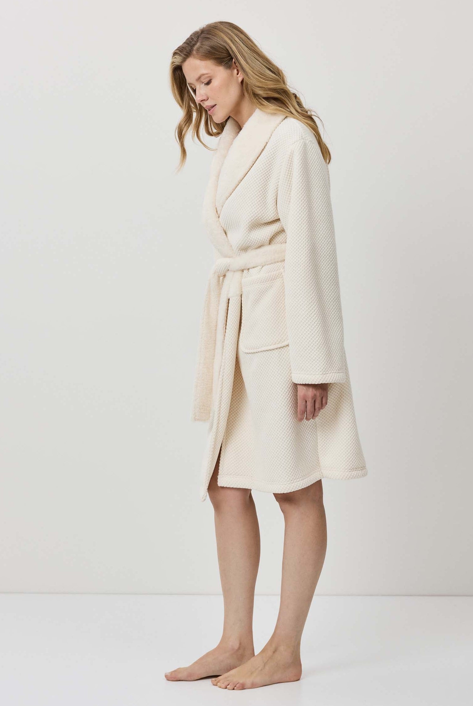 Woman wearing a cream-colored robe against a white background