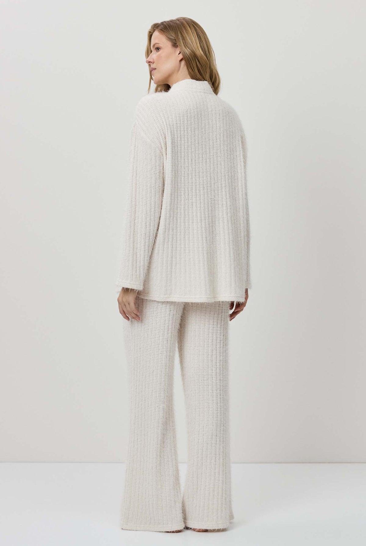 Woman wearing a white ribbed knit outfit against a plain background