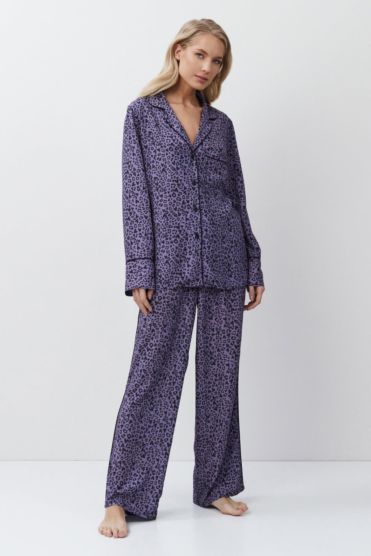 Woman wearing a purple patterned pajama set on a white background