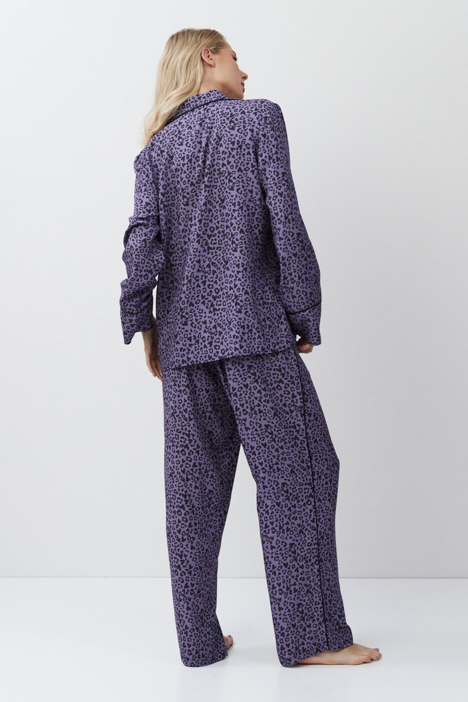 Person wearing a purple patterned pajama set on a white background