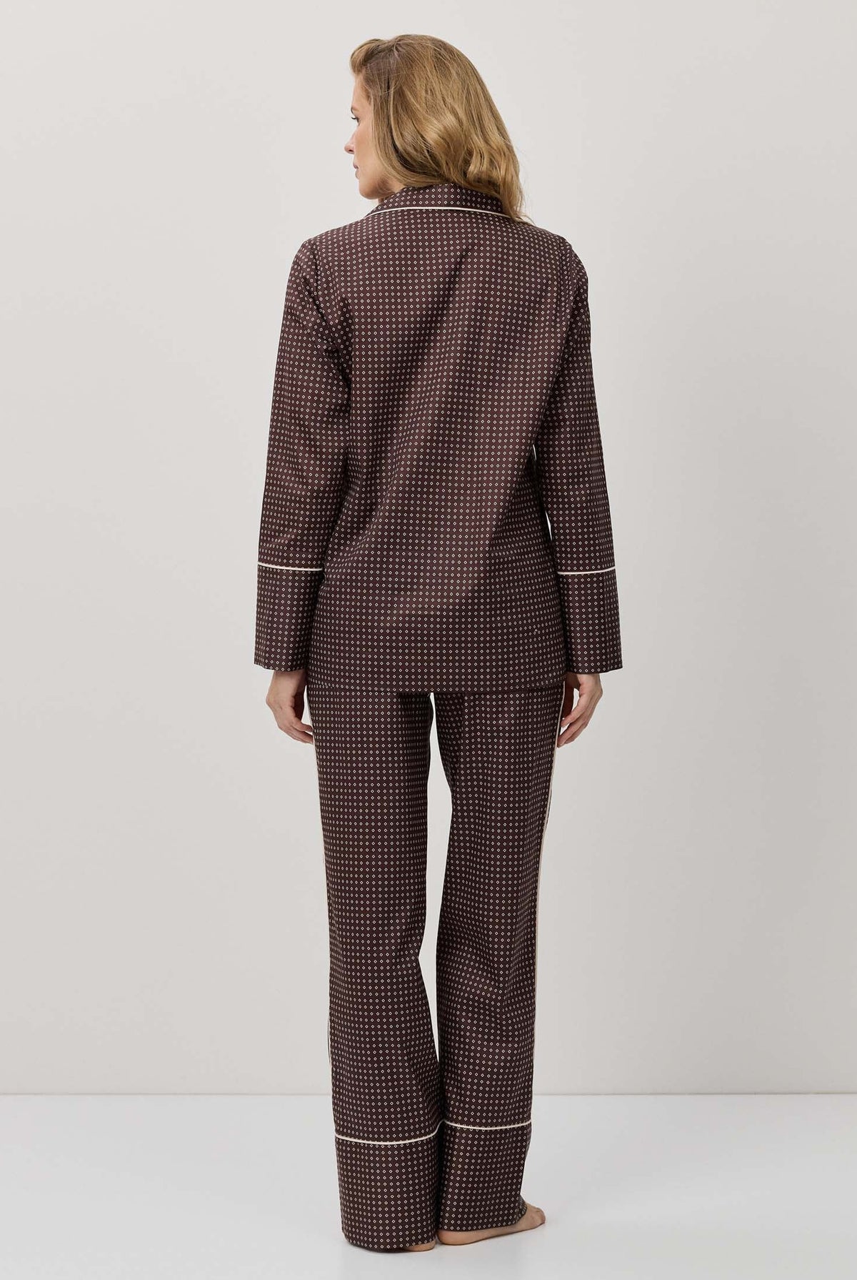 Person wearing a brown checkered pajama set on a white background