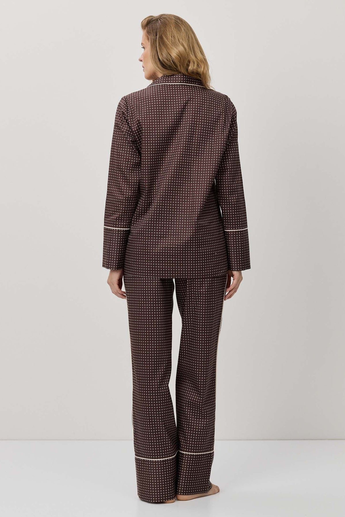 Person wearing a brown checkered pajama set on a white background