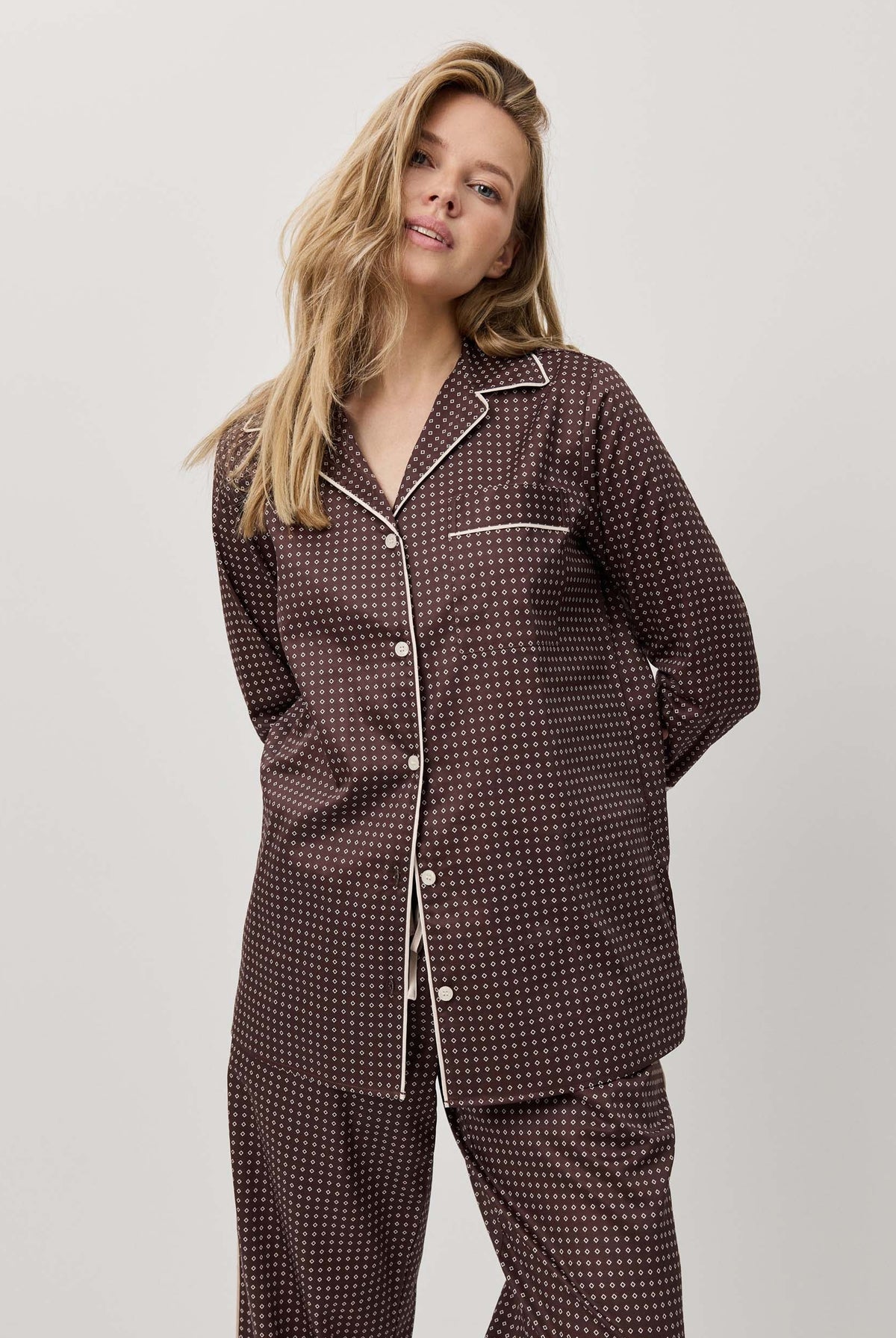 Woman wearing a dark patterned pajama set against a white background