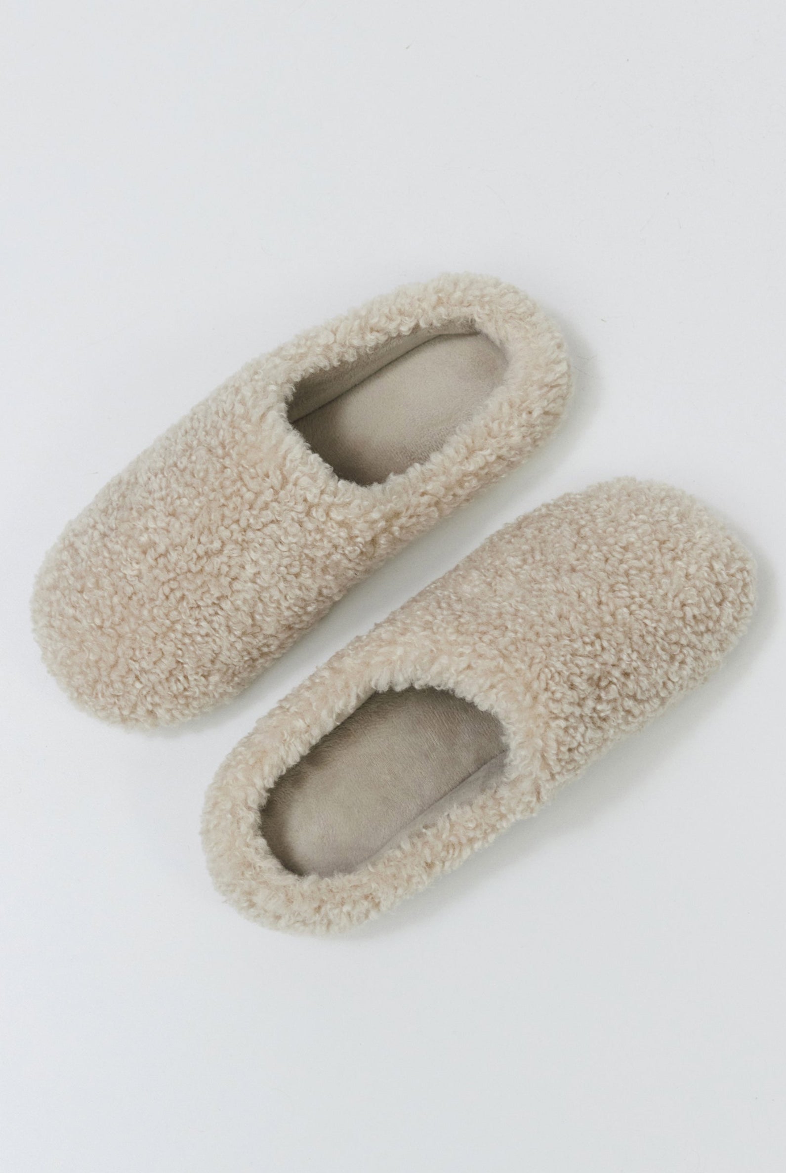 Pair of beige slippers on a light gray background