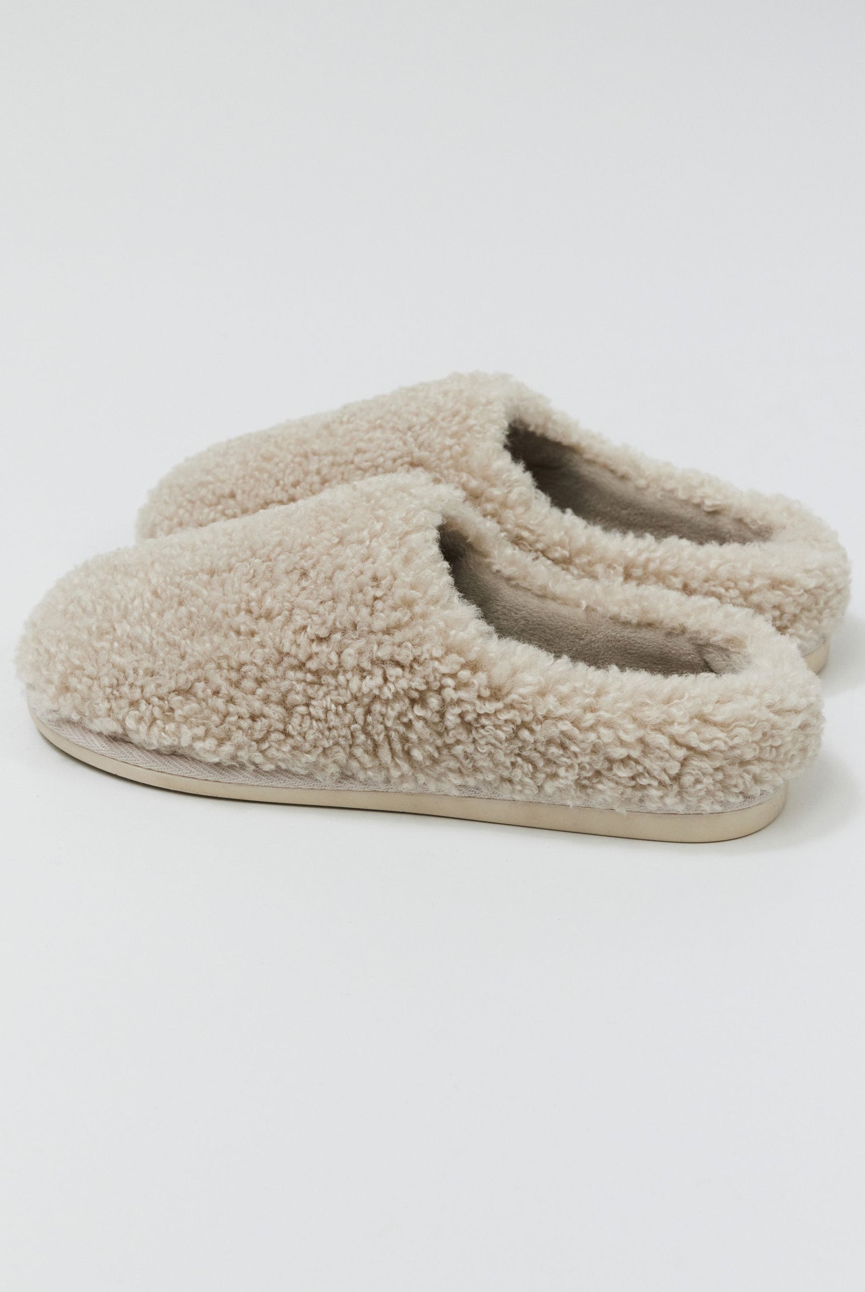 Pair of beige slippers on a white background