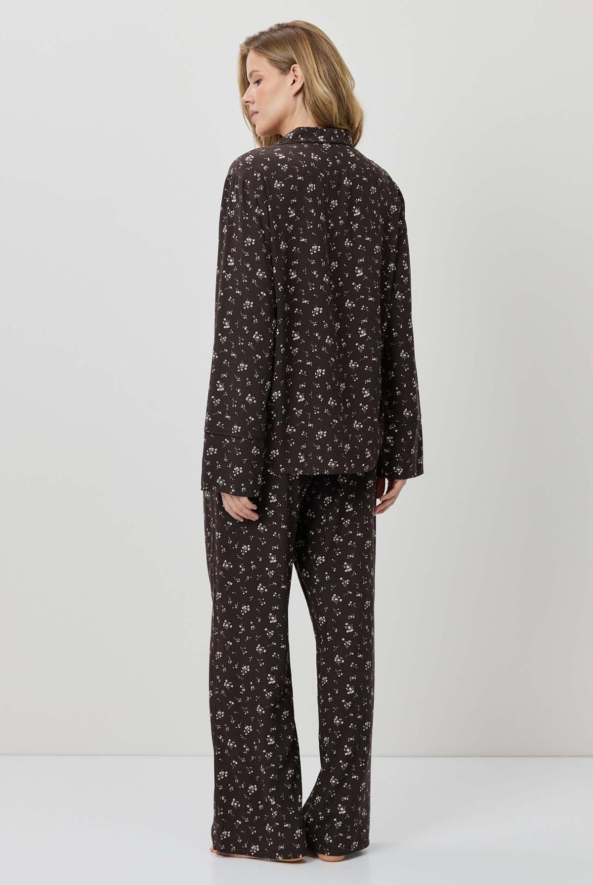 Woman wearing a black patterned pajama set on a white background
