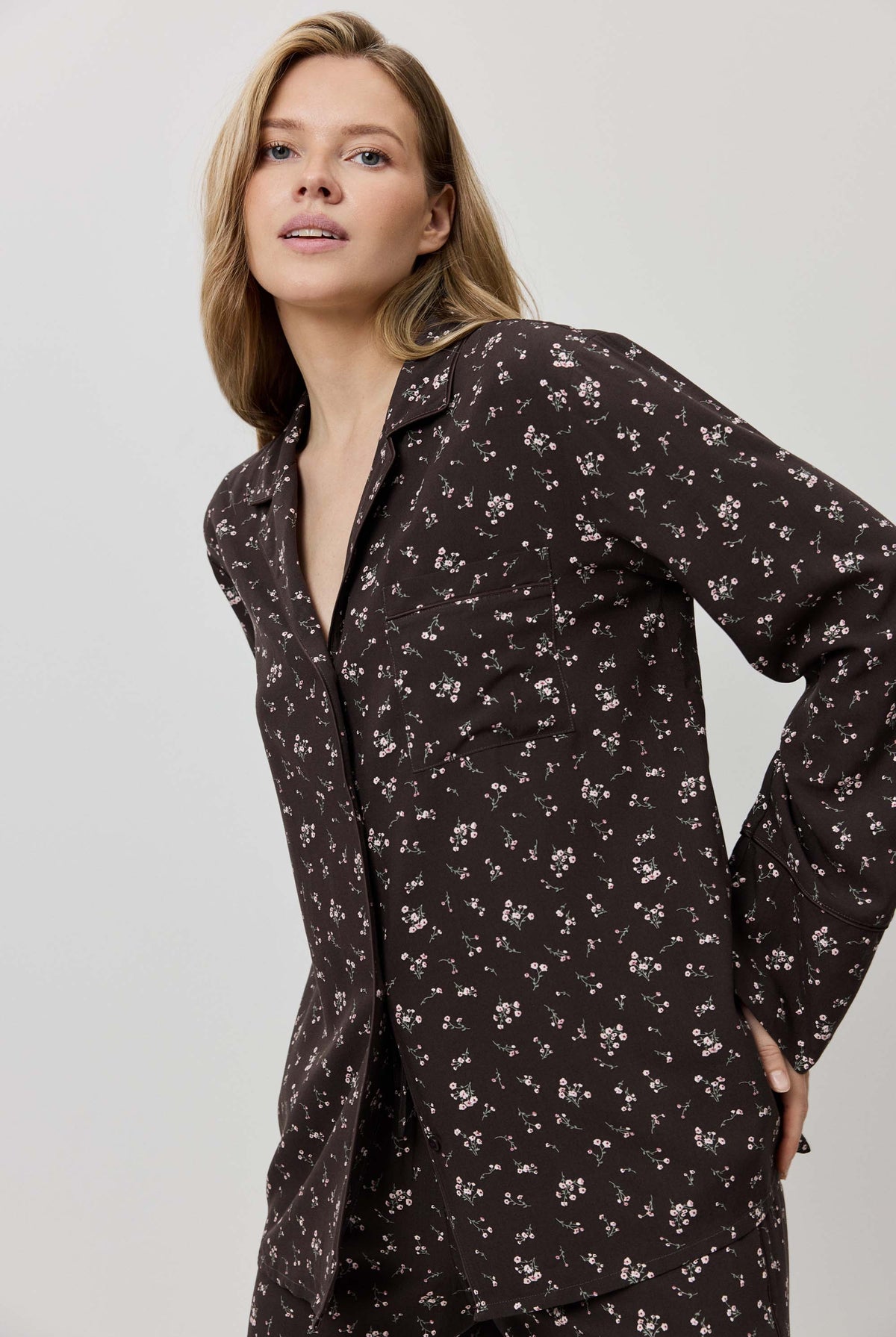 Woman wearing a dark floral patterned shirt dress against a plain background