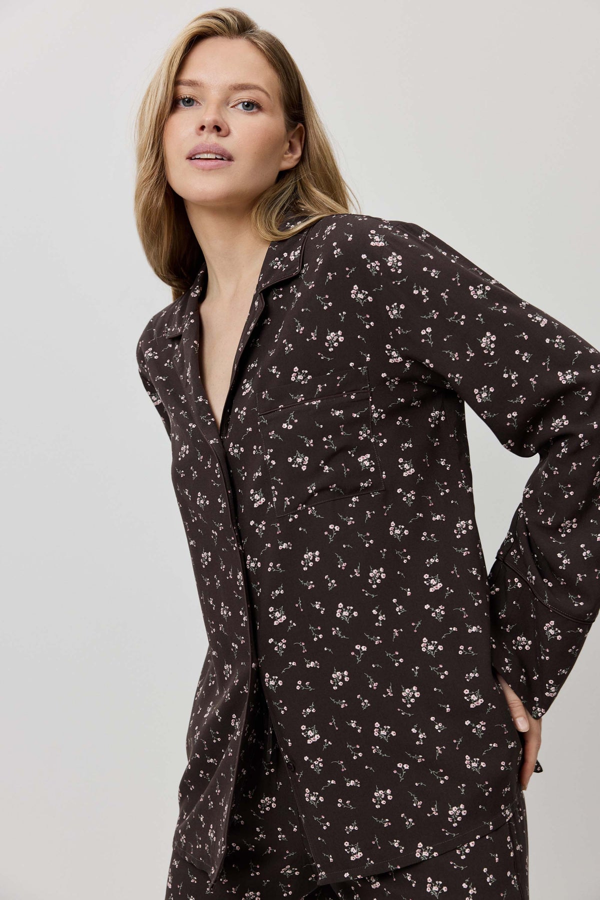 Woman wearing a dark floral patterned shirt dress against a plain background
