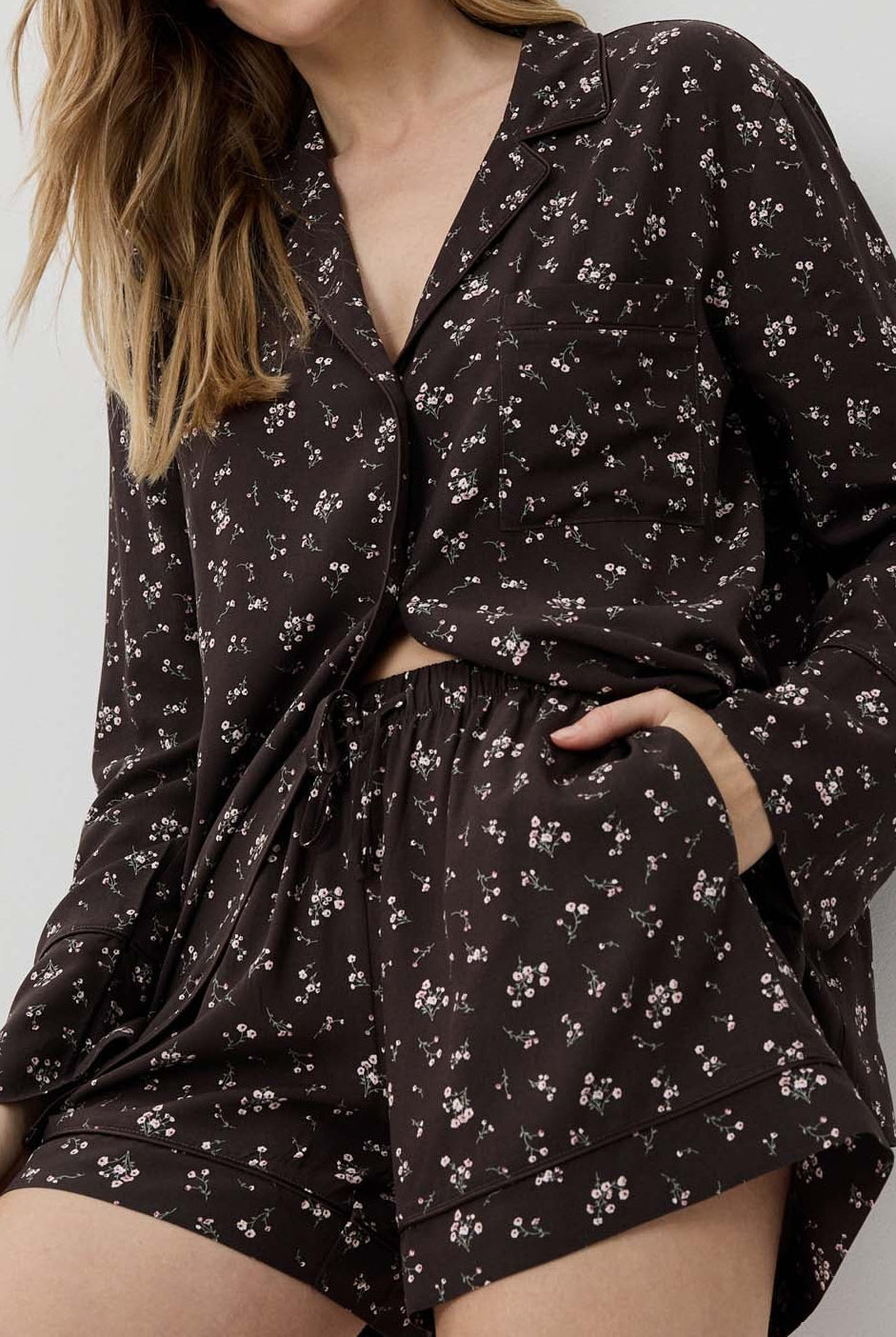 Woman wearing a dark floral pajama set against a light background