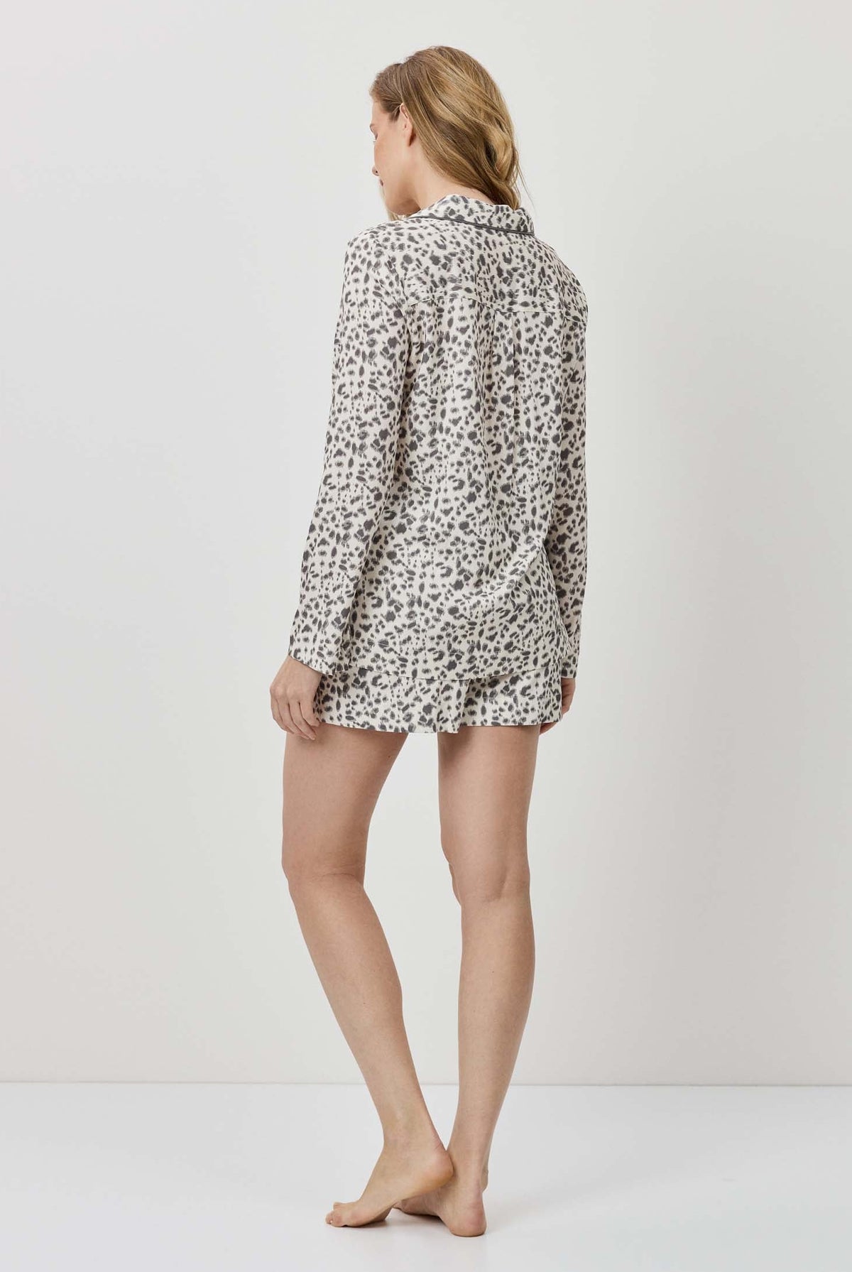 Person wearing a patterned shirt and shorts on a white background