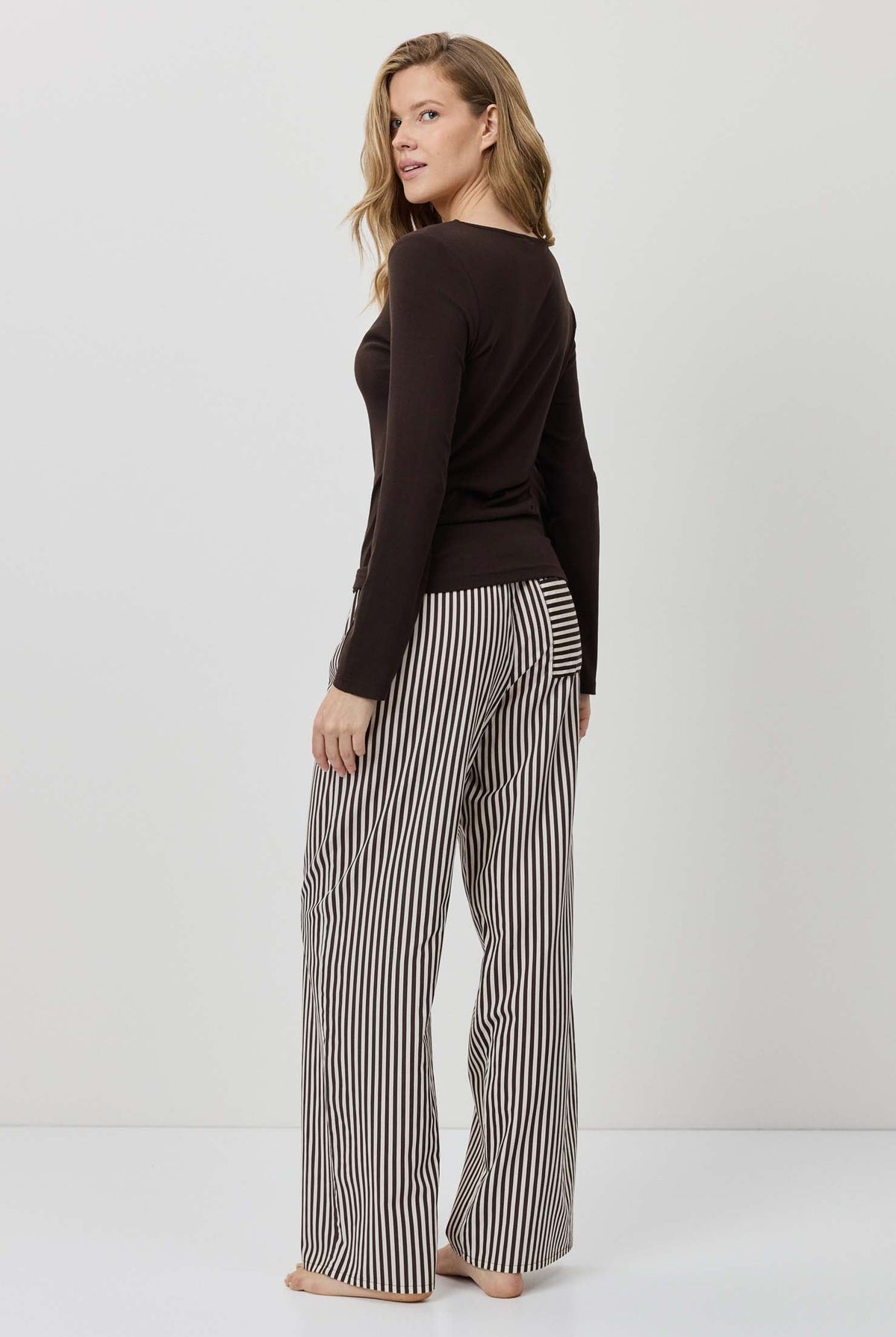 Woman wearing a black top and striped pants on a white background