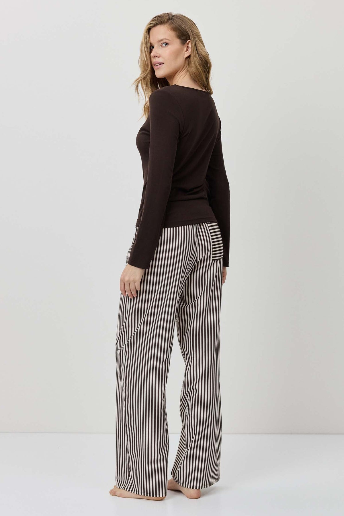 Woman wearing a black top and striped pants on a white background