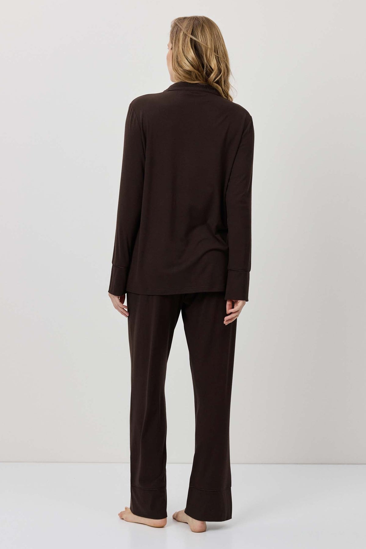 Person wearing a brown outfit standing against a plain background