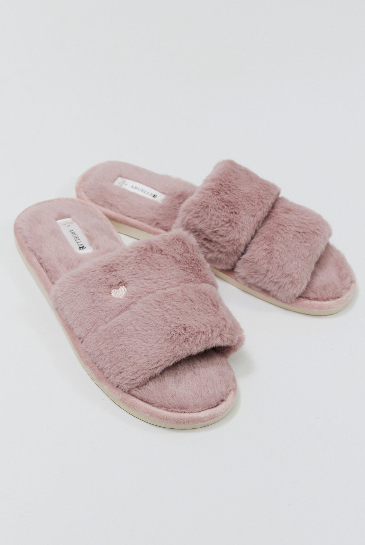 Pair of pink fuzzy slippers on a light gray background