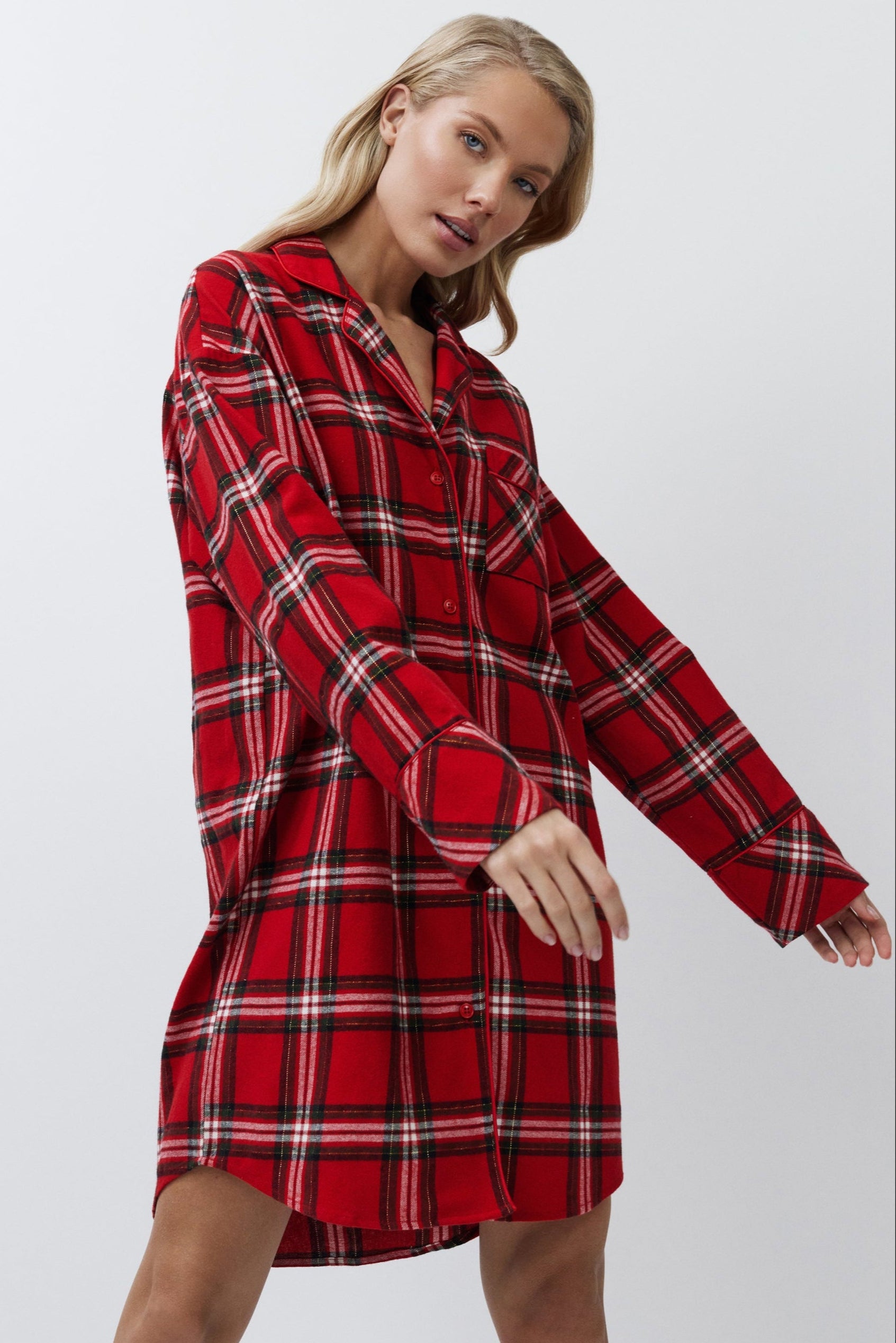 Woman wearing a red plaid shirt dress against a white background
