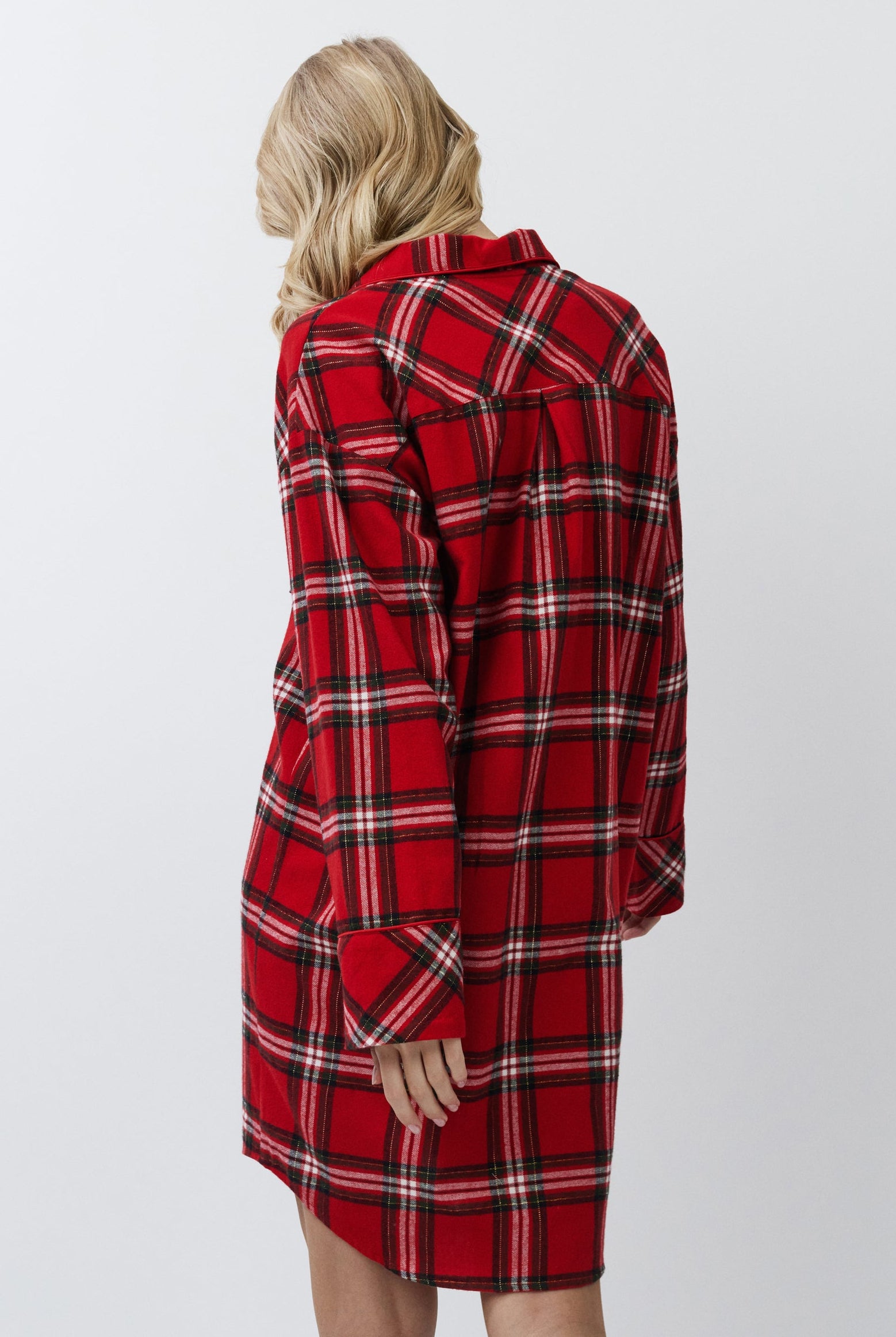 Person wearing a red plaid shirt dress against a white background