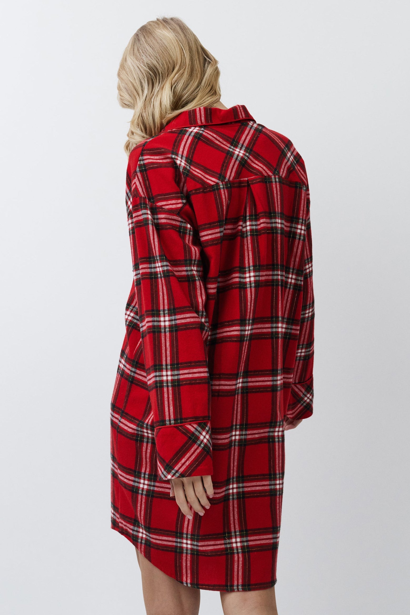 Person wearing a red plaid shirt dress against a white background