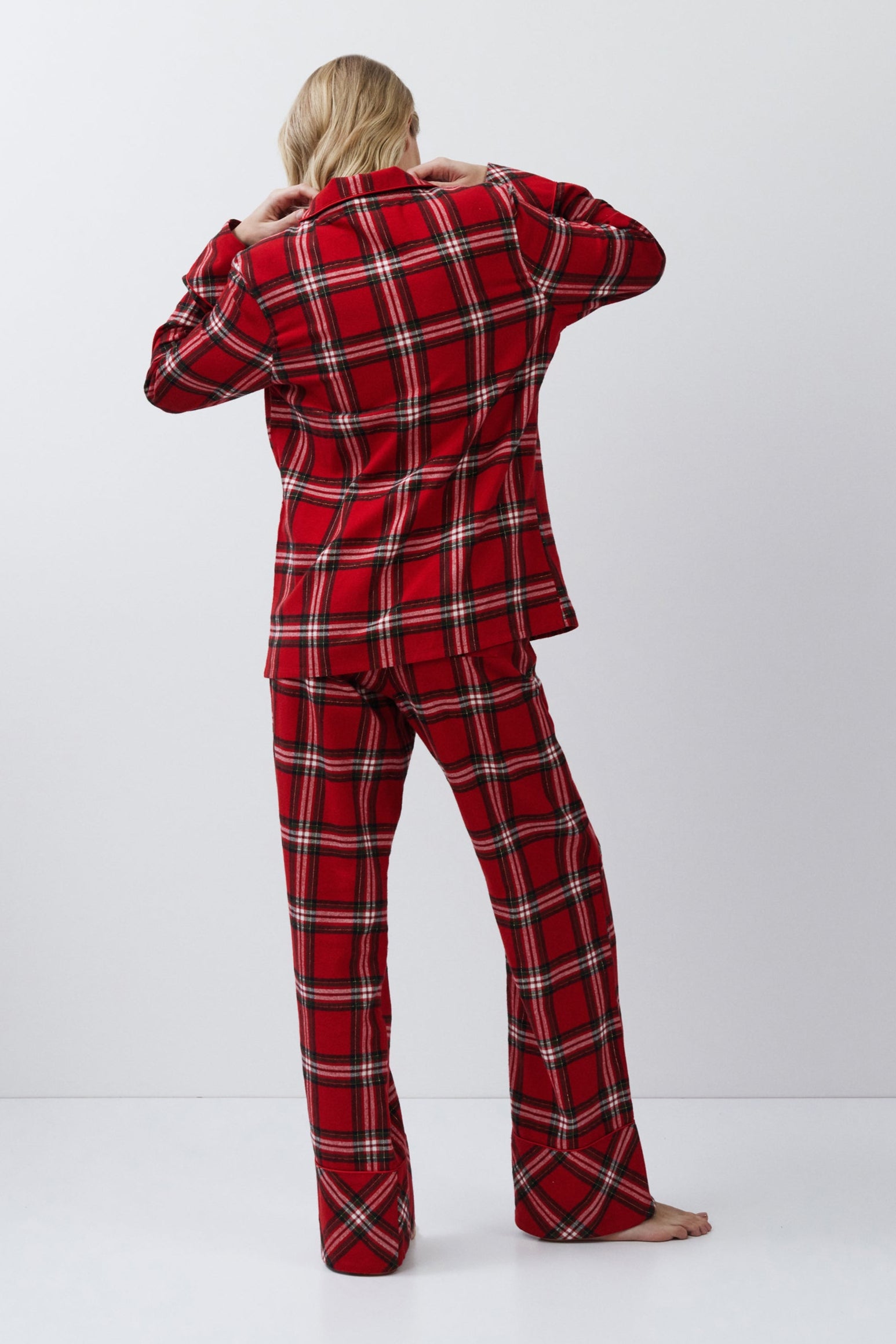 Person wearing a red plaid pajama set on a white background
