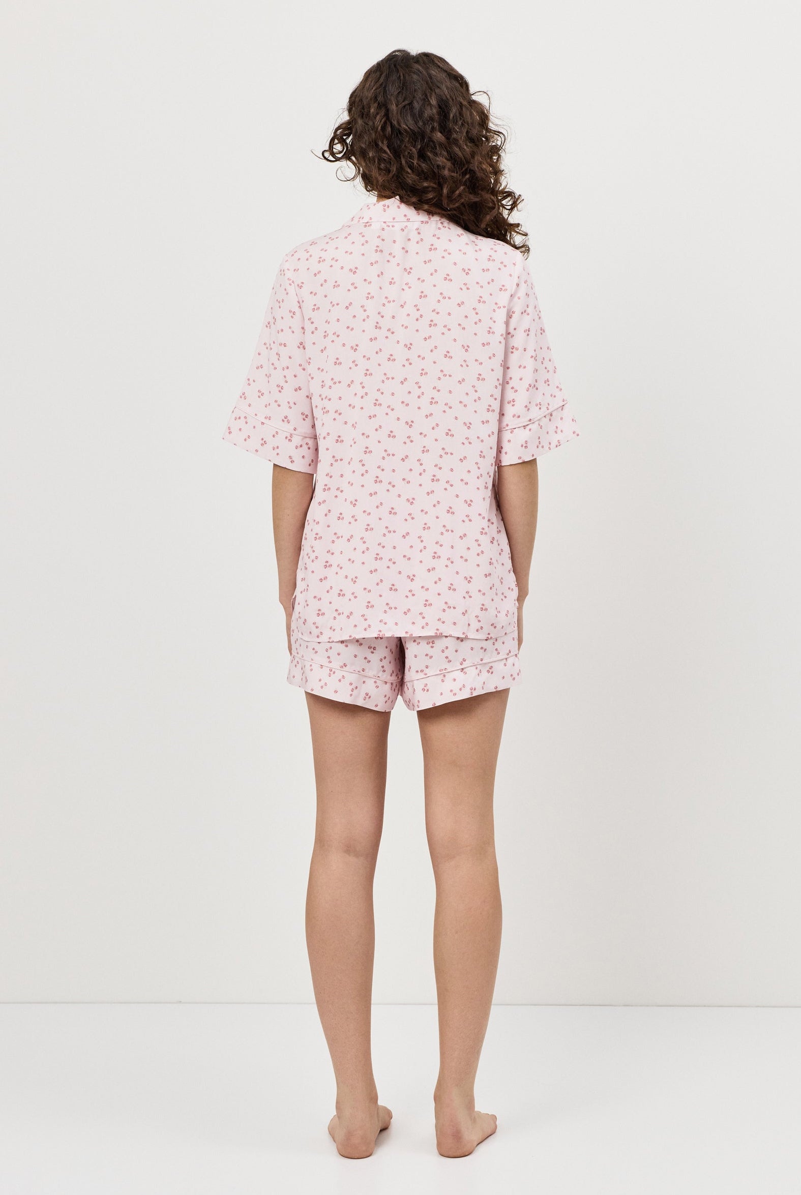 Person wearing a pink pajama set with a white background