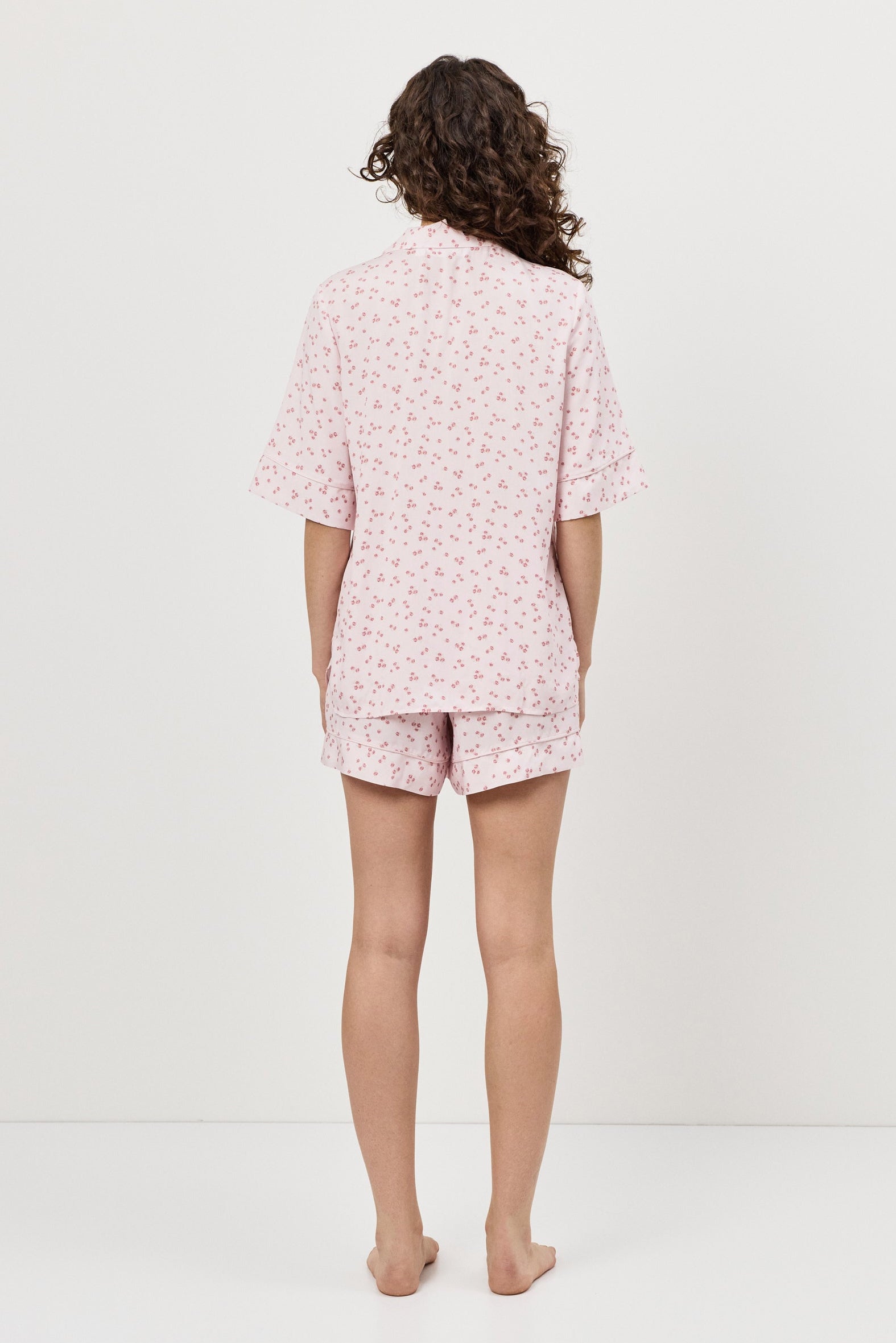 Person wearing a pink pajama set with a white background