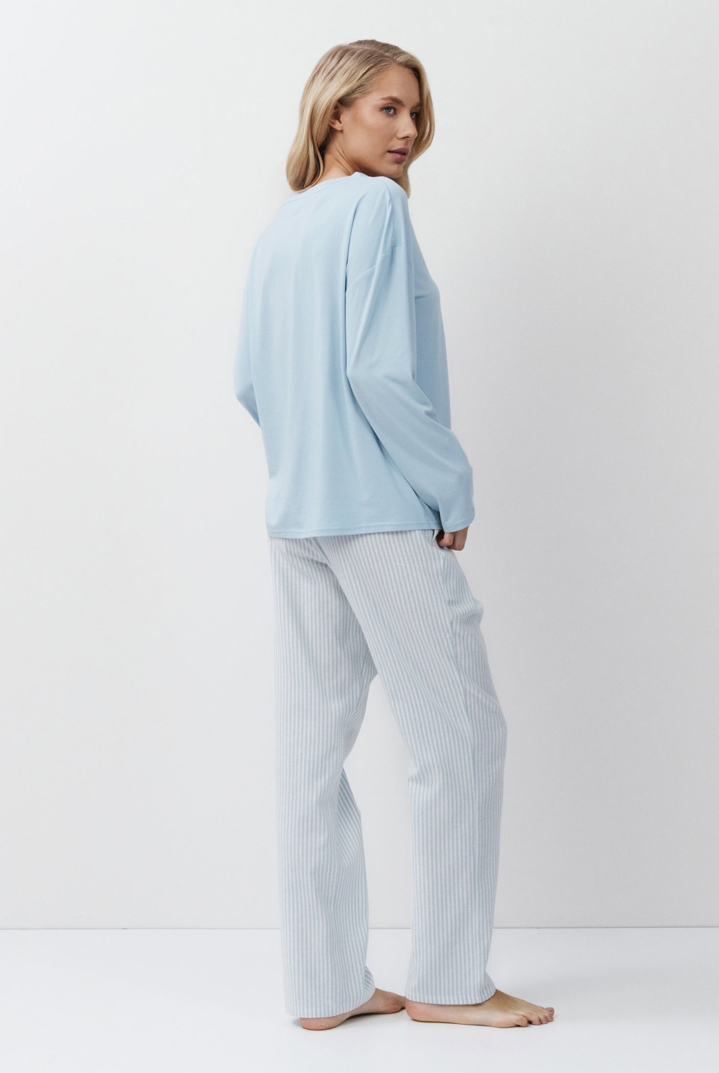 Woman wearing a light blue pajama set on a white background