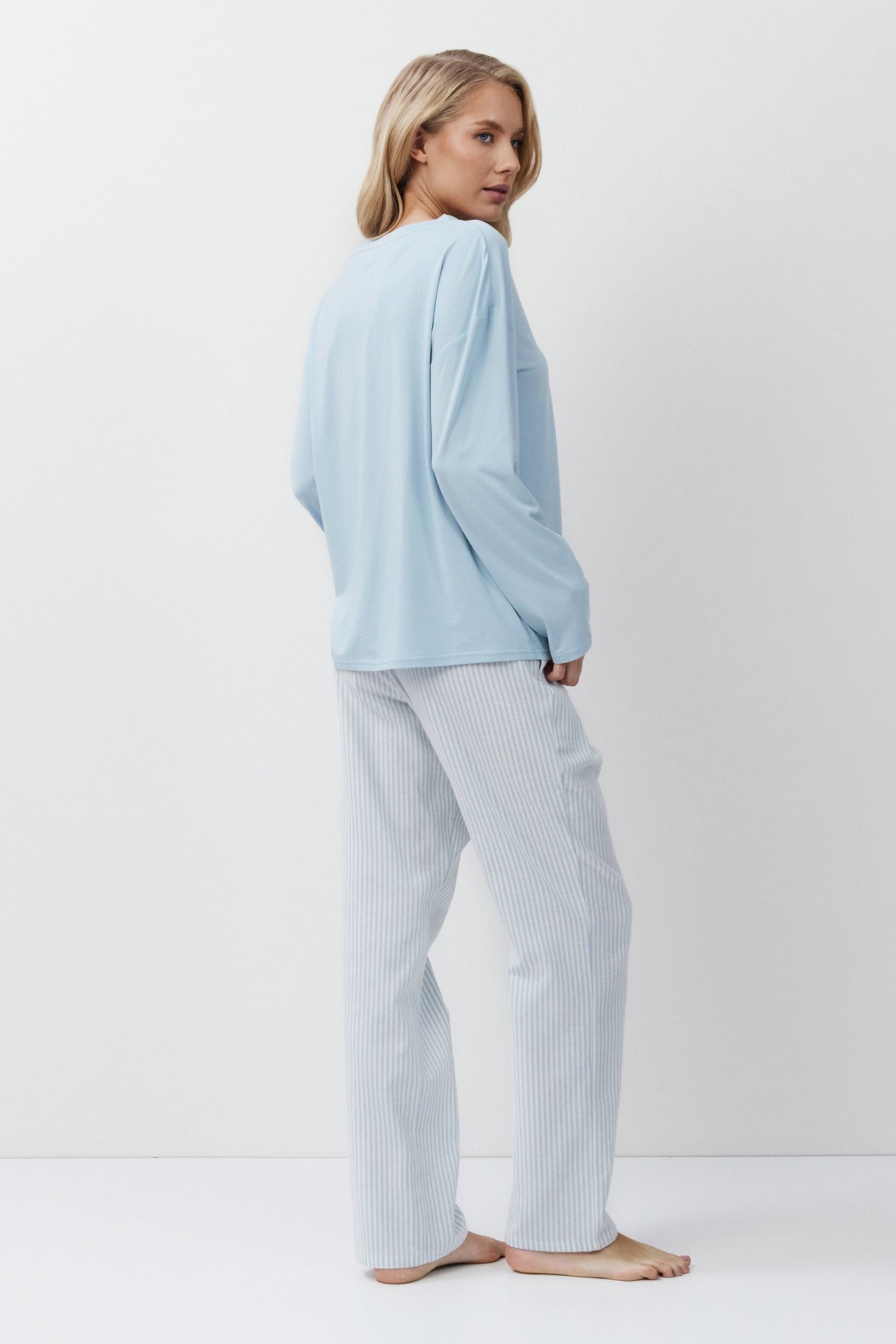 Woman wearing a light blue pajama set on a white background