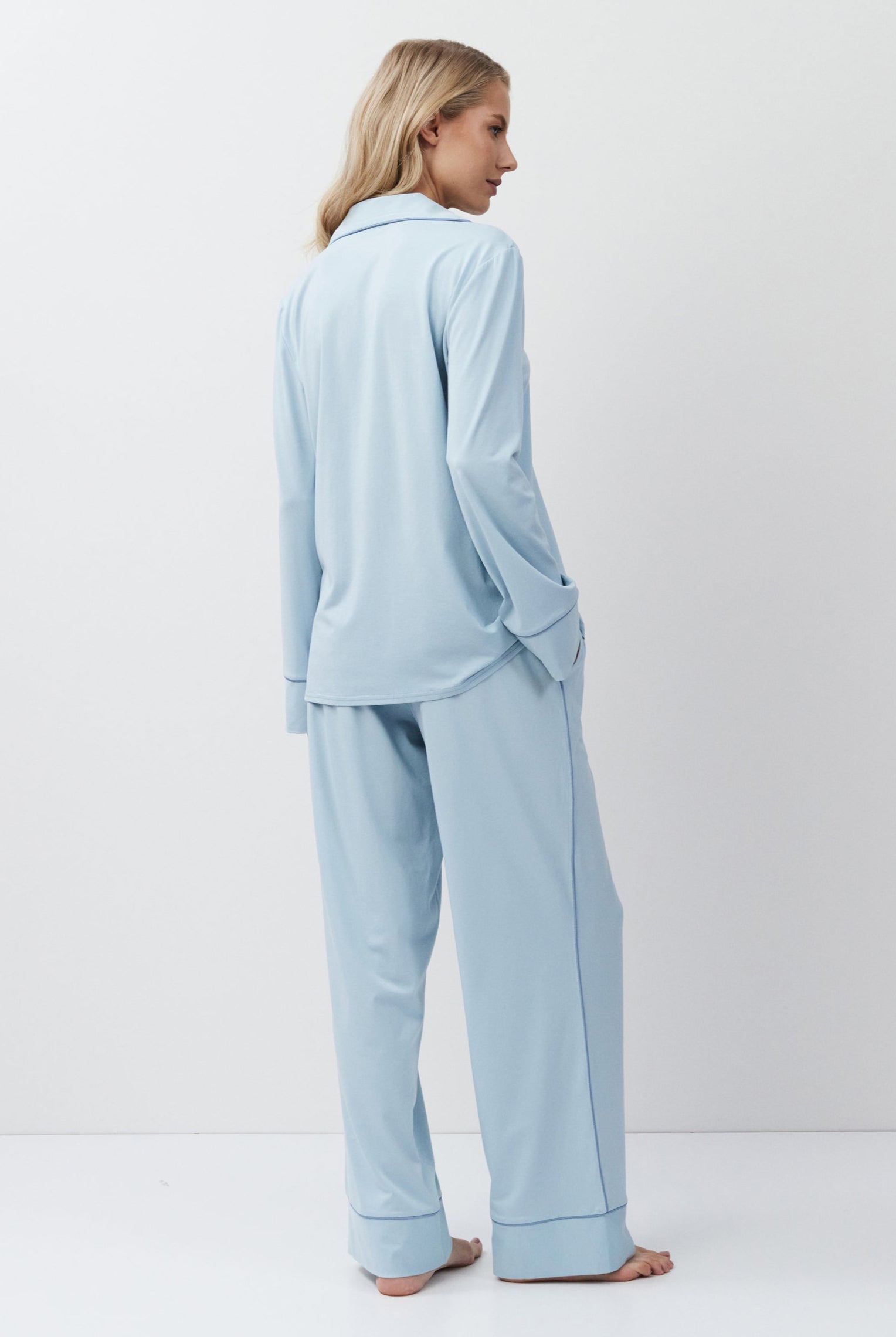 Woman wearing light blue pajamas against a white background