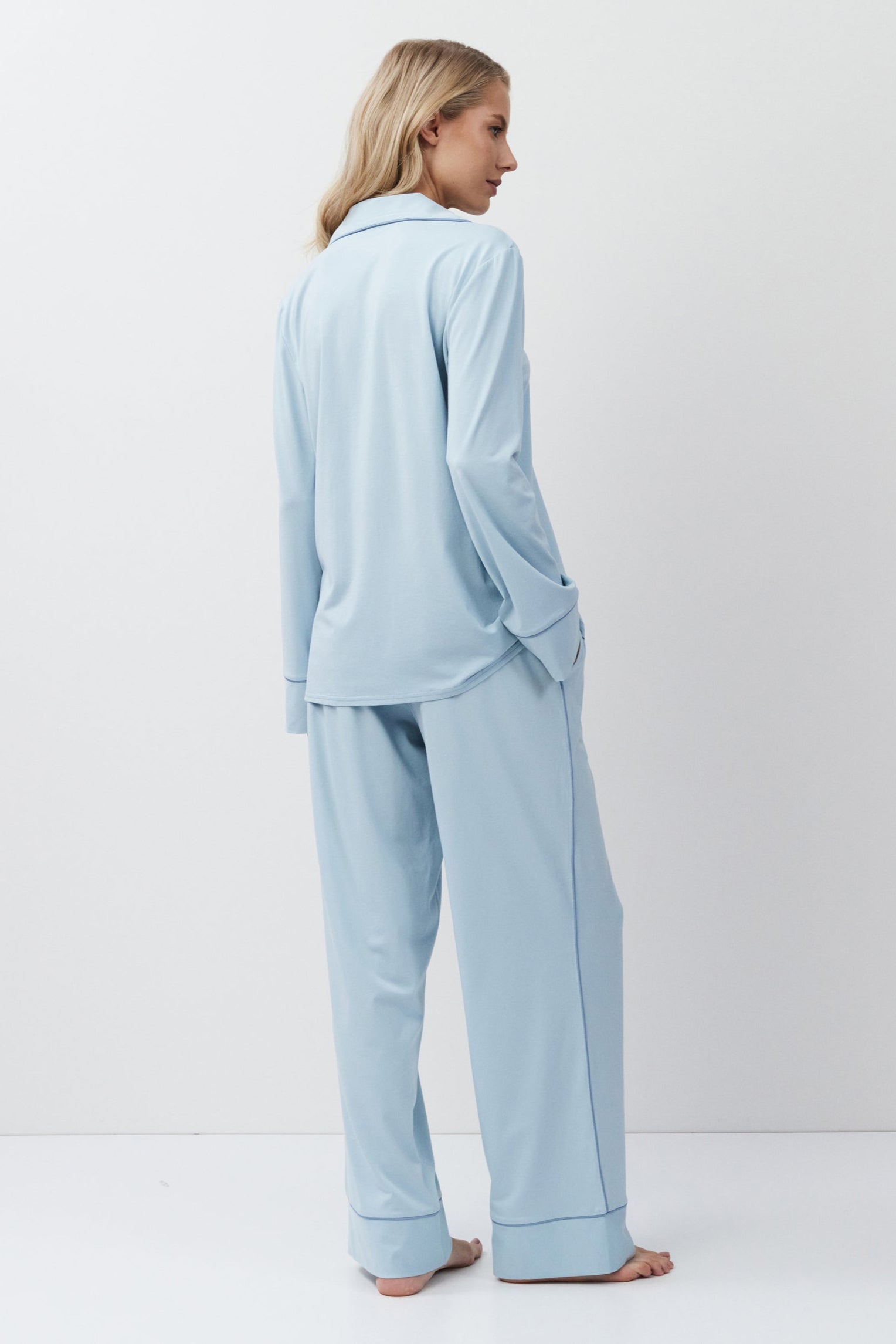Woman wearing light blue pajamas against a white background