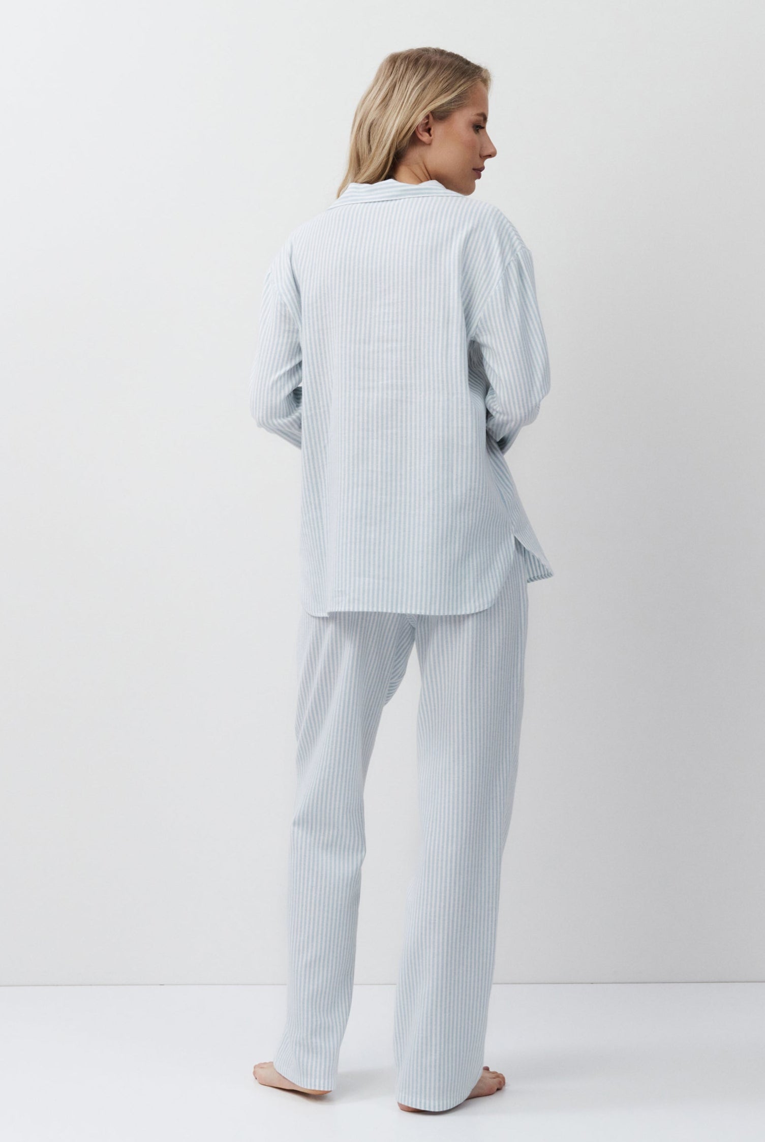 Woman wearing a light blue outfit standing against a white background