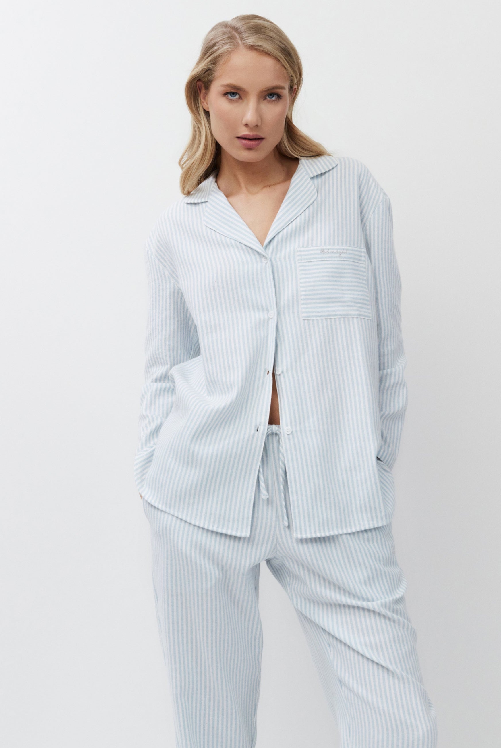 Woman wearing light blue striped pajamas against a white background