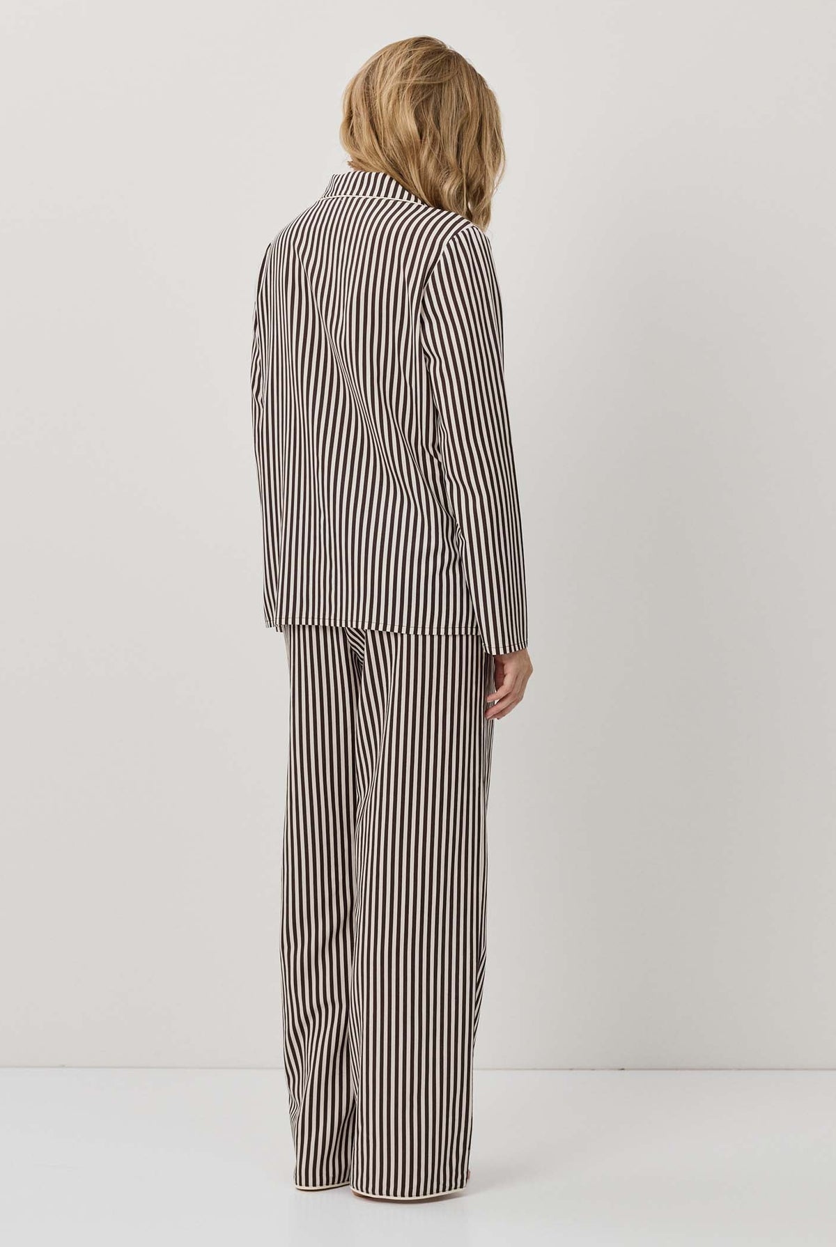 Person wearing a striped suit standing against a white background