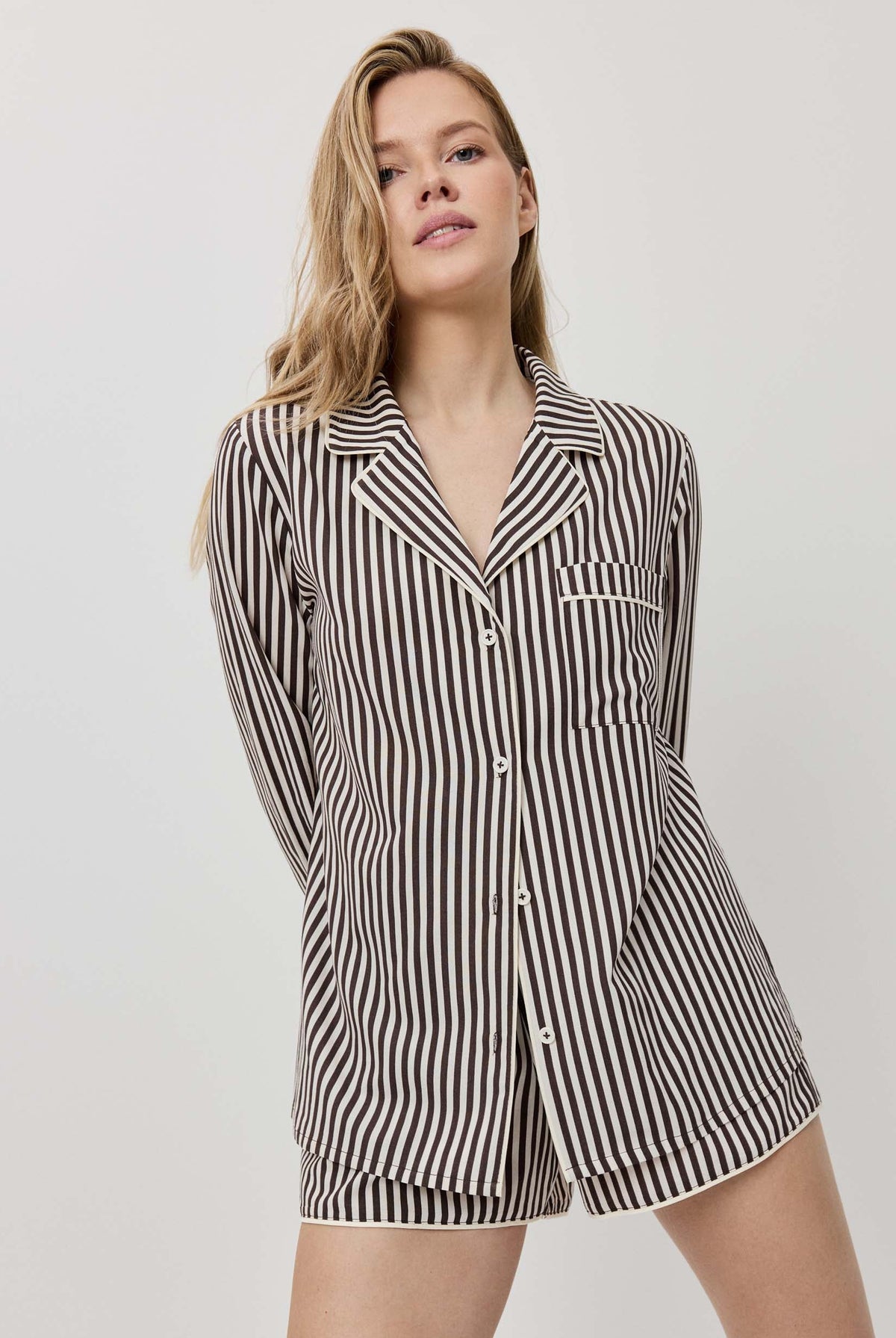Woman wearing a black and white striped pajama set on a plain background