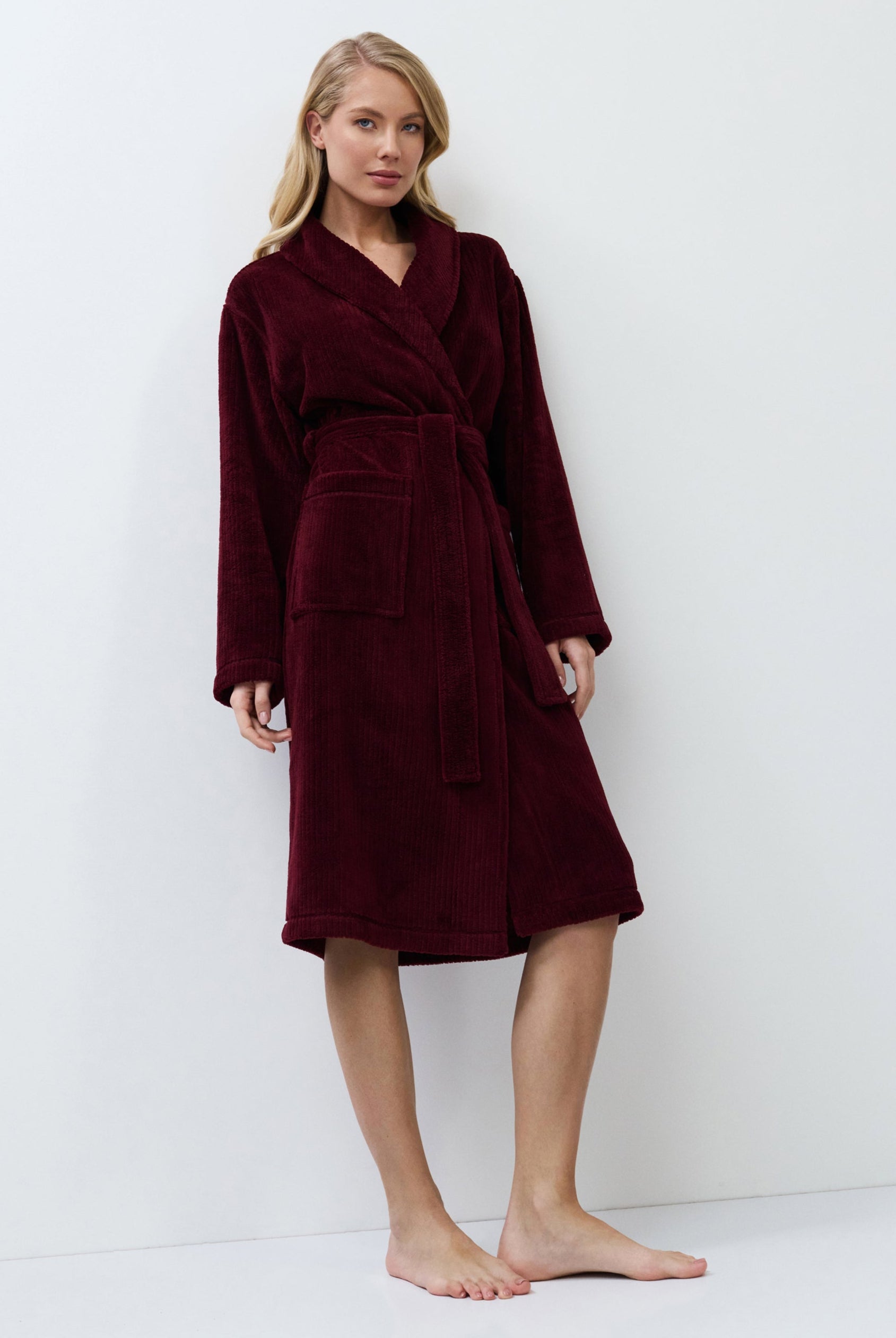 Woman wearing a burgundy robe against a white background