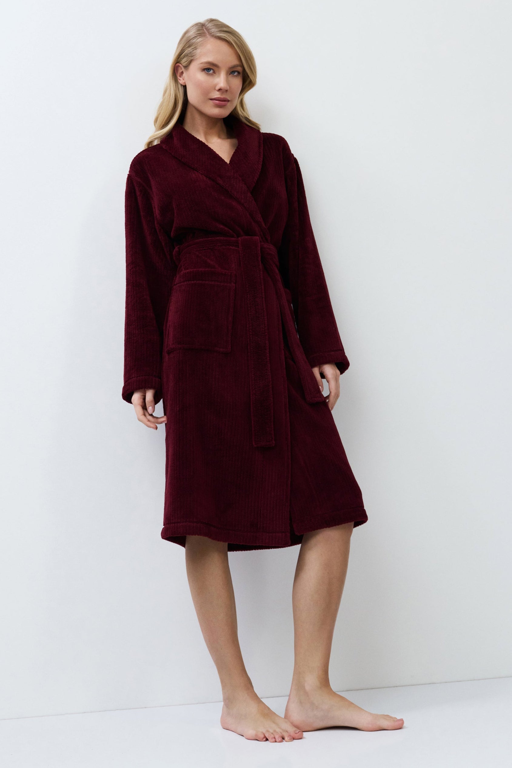 Woman wearing a burgundy robe against a white background
