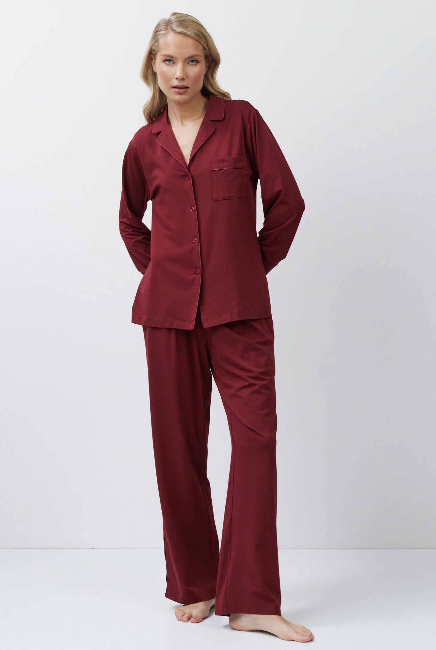 Woman wearing a burgundy pajama set against a white background