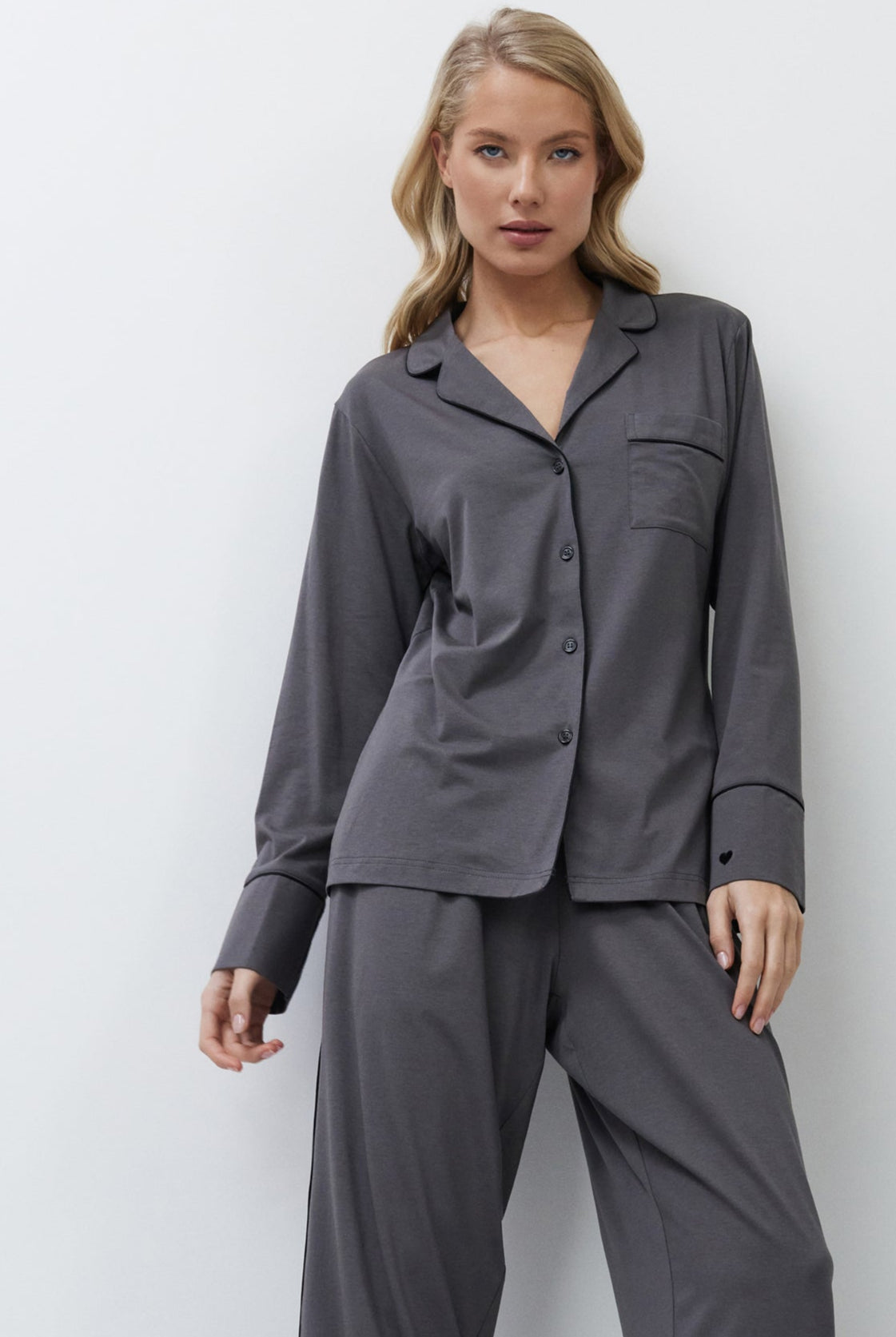 Woman wearing gray pajama set against a white background