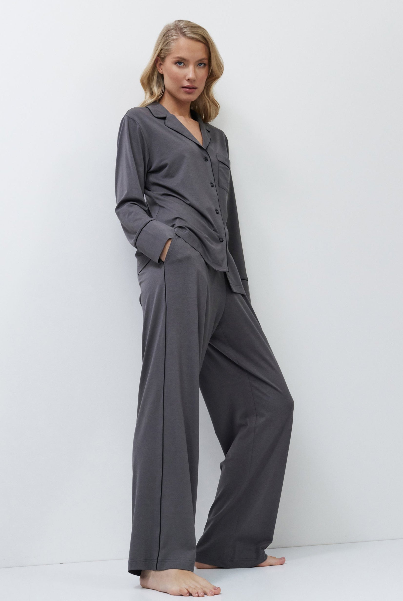 Woman wearing gray pajamas standing against a white background