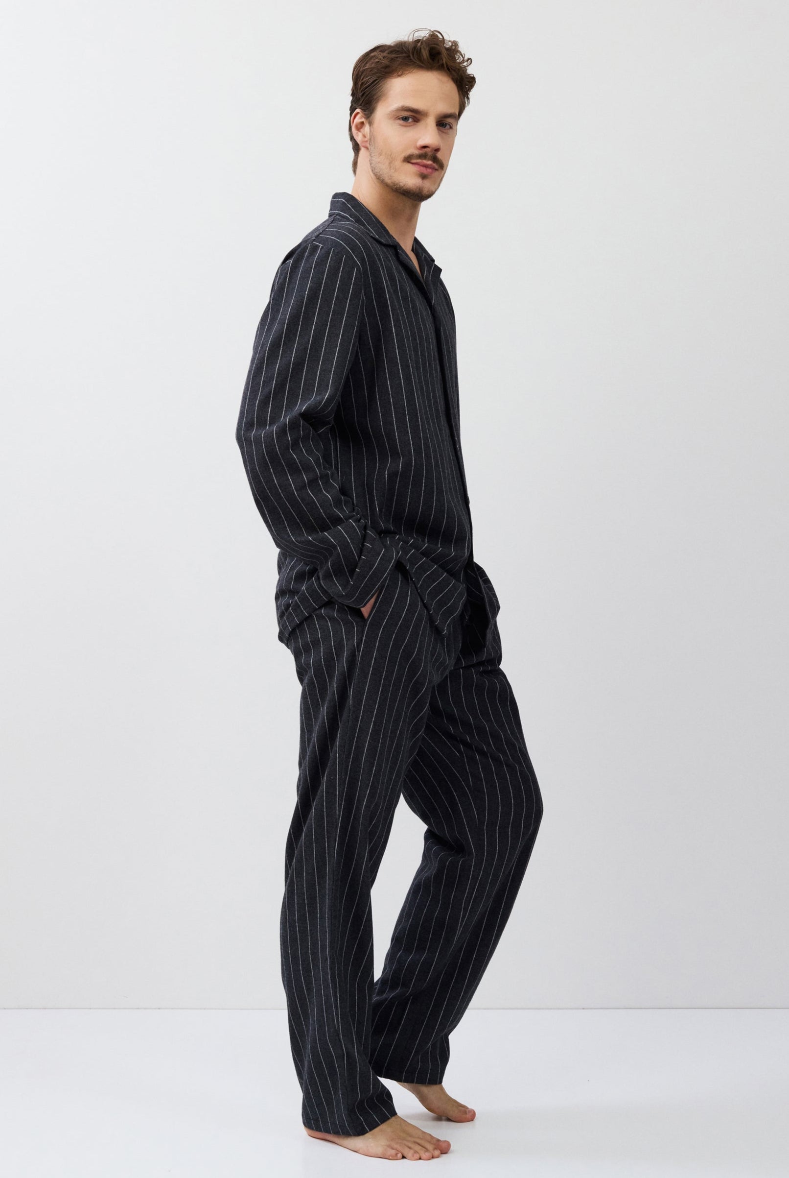 Man wearing a dark striped pajama set on a white background