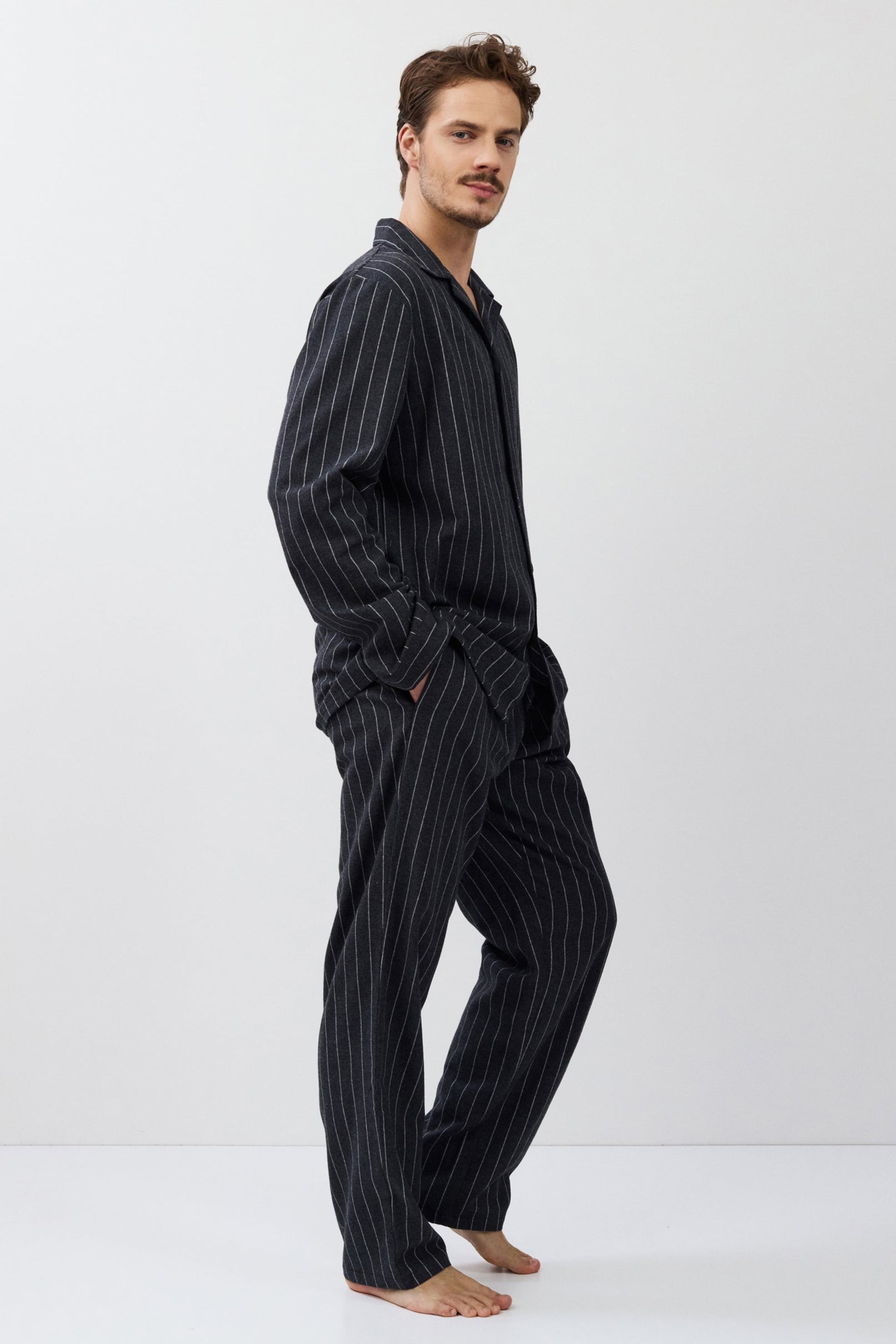 Man wearing a dark striped pajama set on a white background