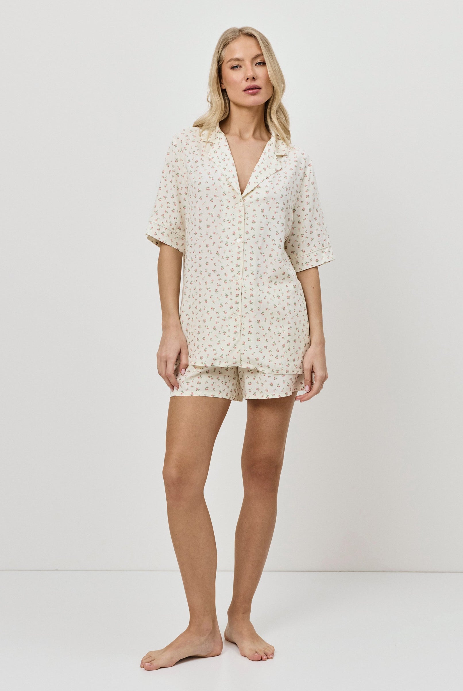 Woman wearing a butter yellow pajama set on a plain background