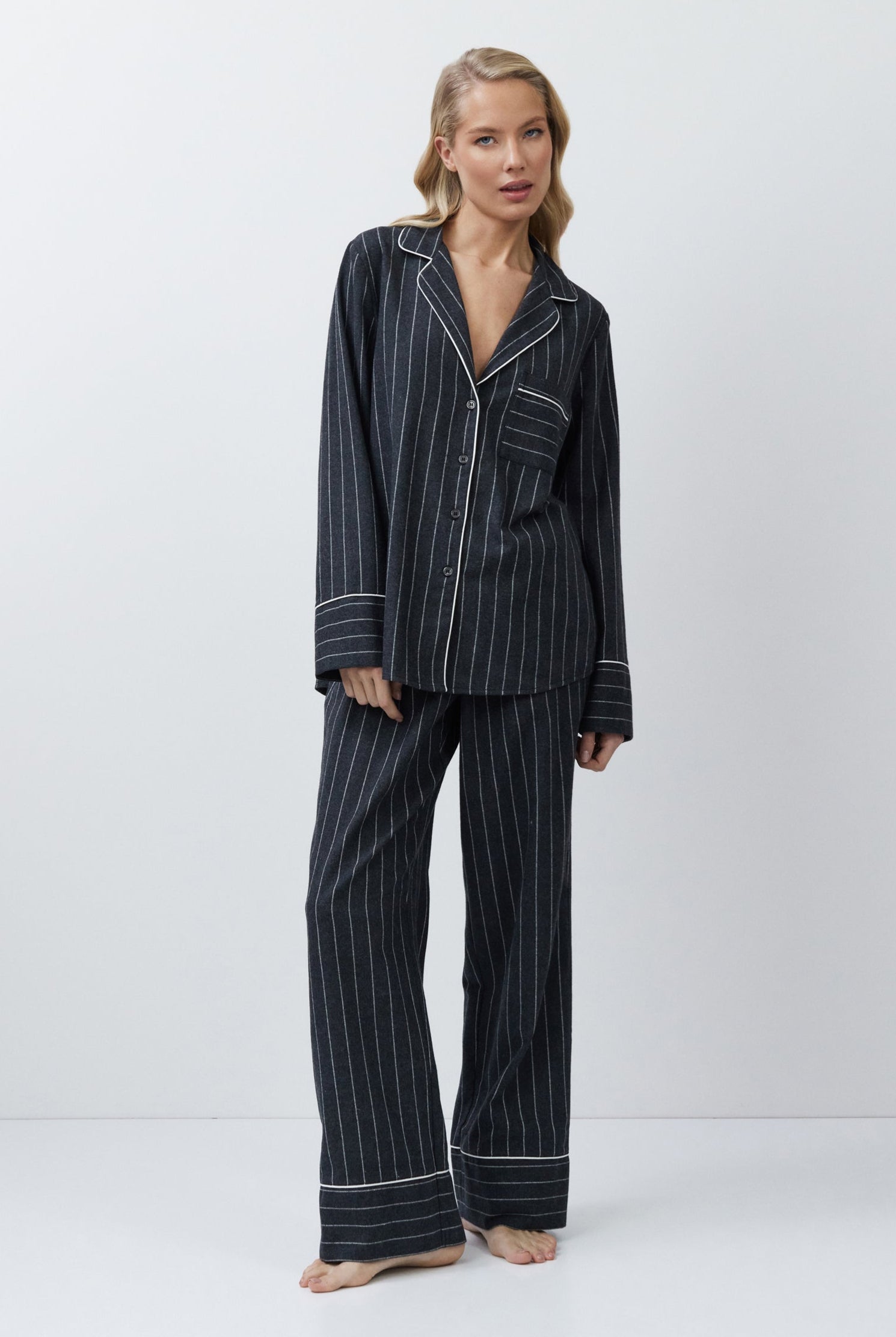 Woman wearing a gray pinstripe pajama set on a white background