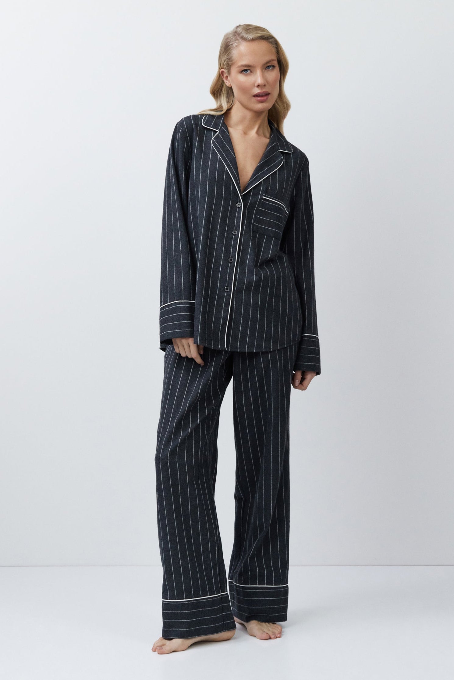 Woman wearing a gray pinstripe pajama set on a white background