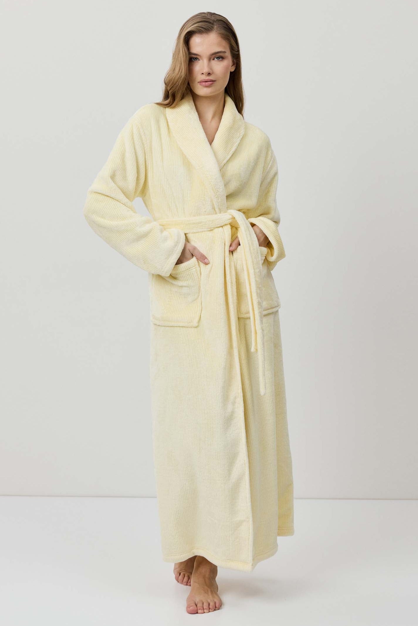 Woman wearing a light yellow bathrobe against a white background