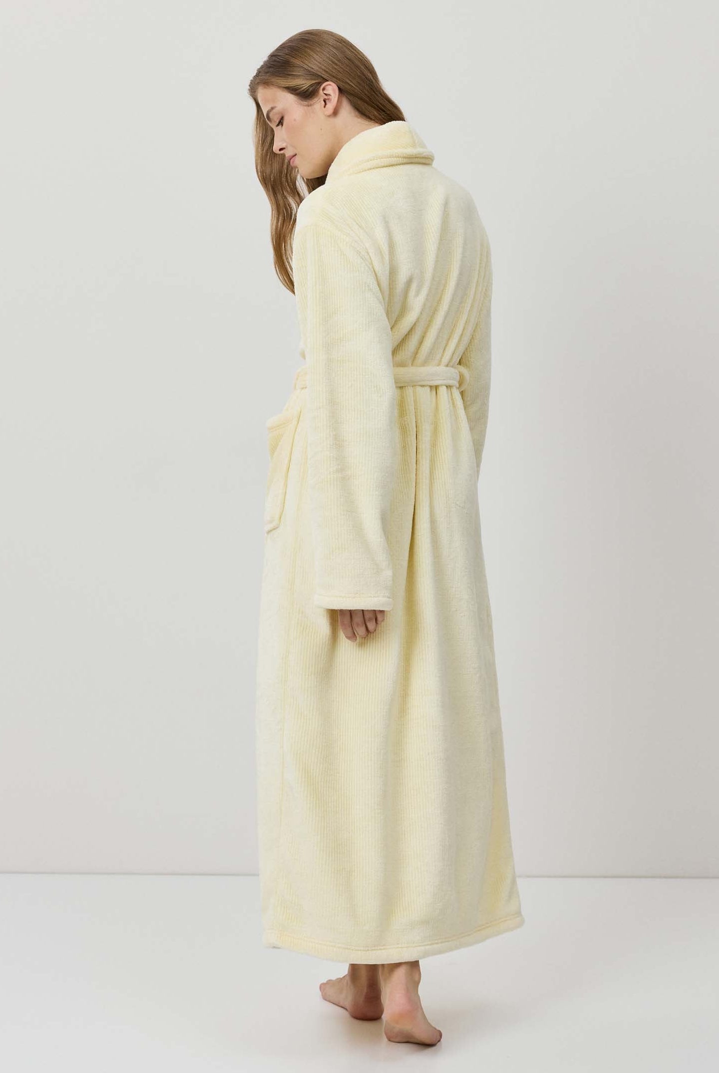 Woman wearing a long cream-colored robe against a white background