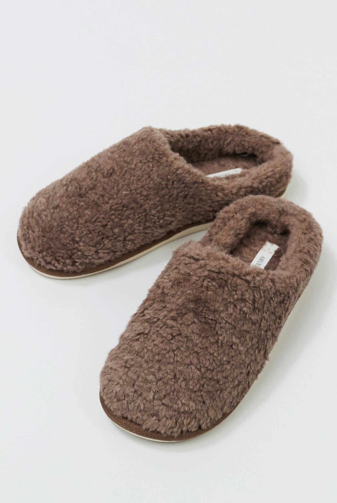 Pair of brown fuzzy slippers on a white background