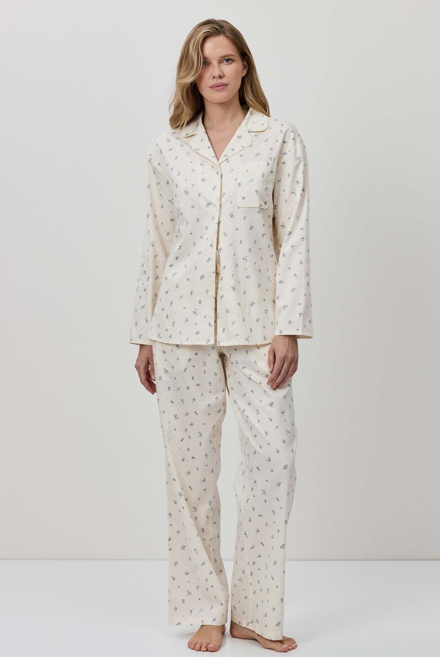 Woman wearing a white pajama set with a subtle pattern on a plain background