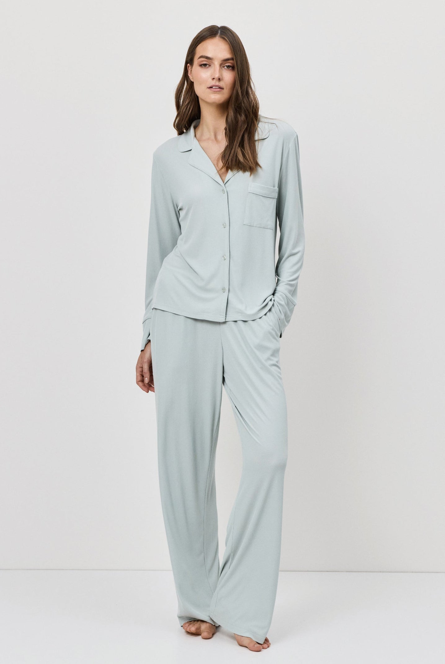 Woman wearing a light blue pajama set against a white background