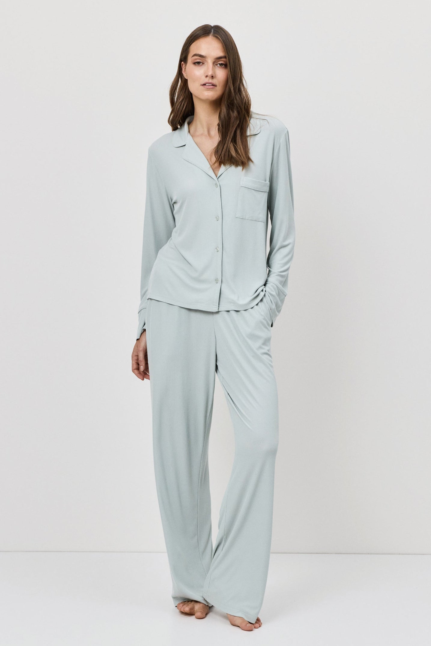 Woman wearing a light blue pajama set against a white background