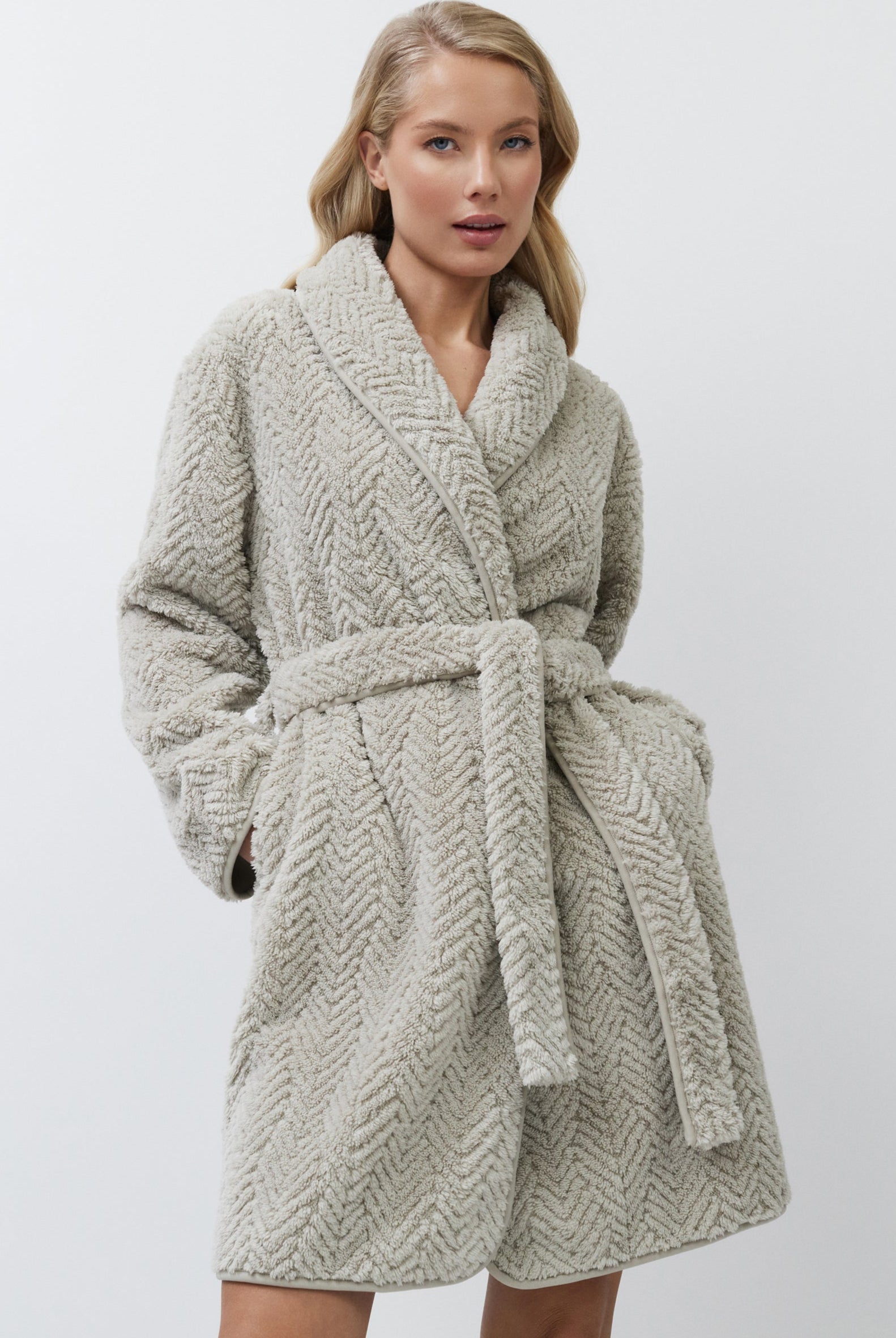 Woman wearing a textured beige bathrobe against a plain background